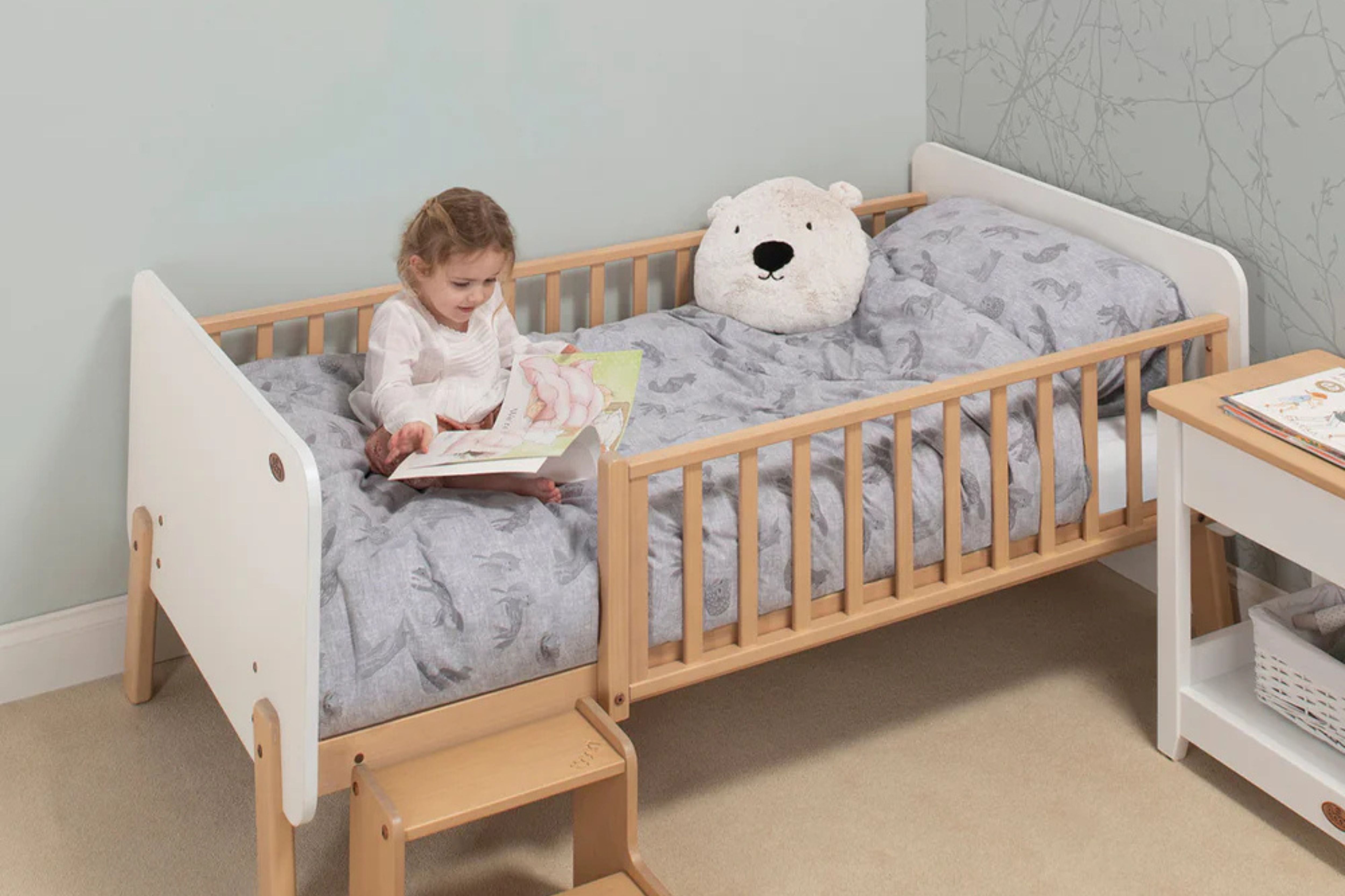 Toddler sitting on the Boori Natty Bedside Bed reading a book in a cosy bedroom setting