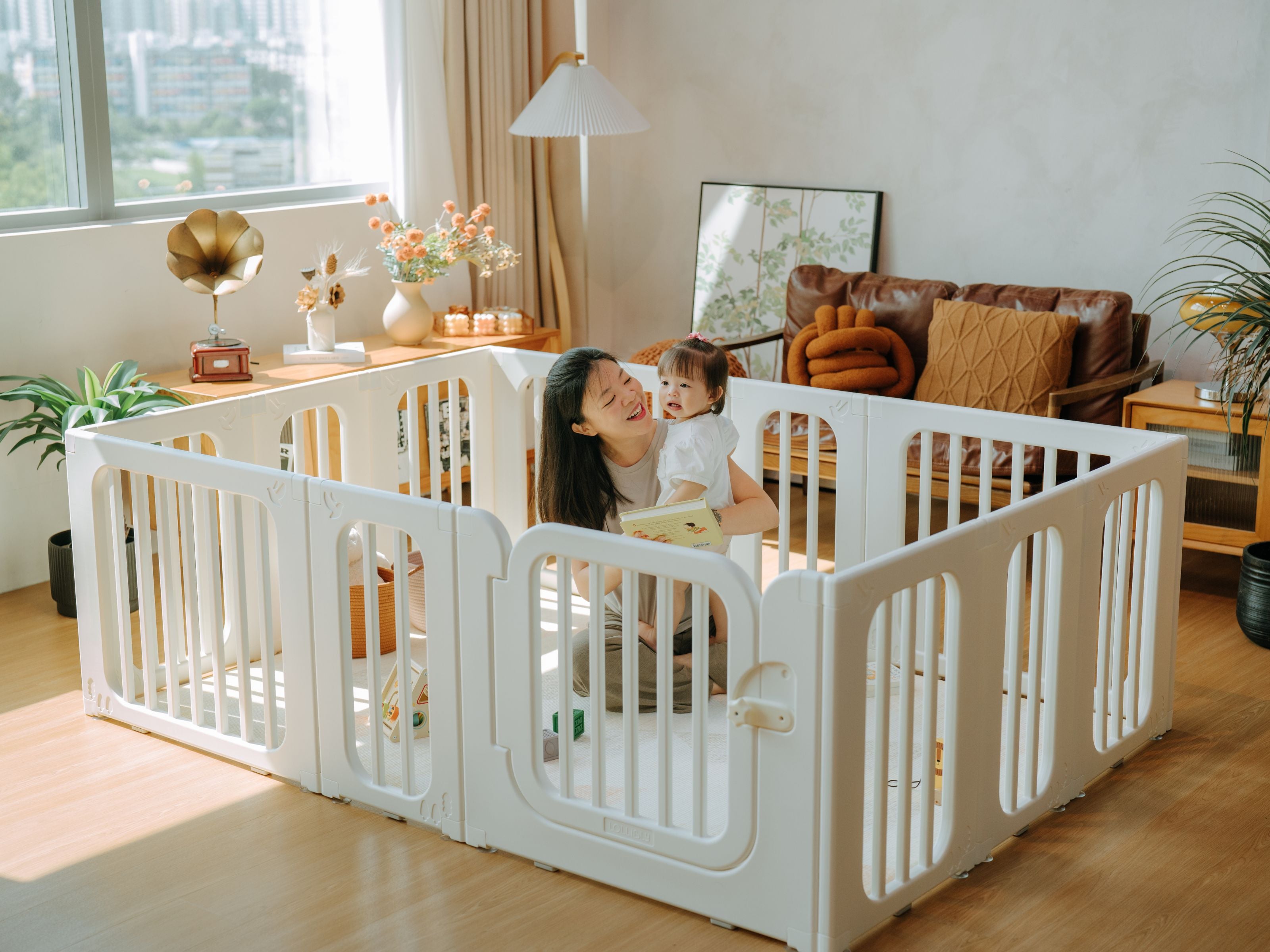Mum cradling her child while seated inside the Meadow playpen in the living room