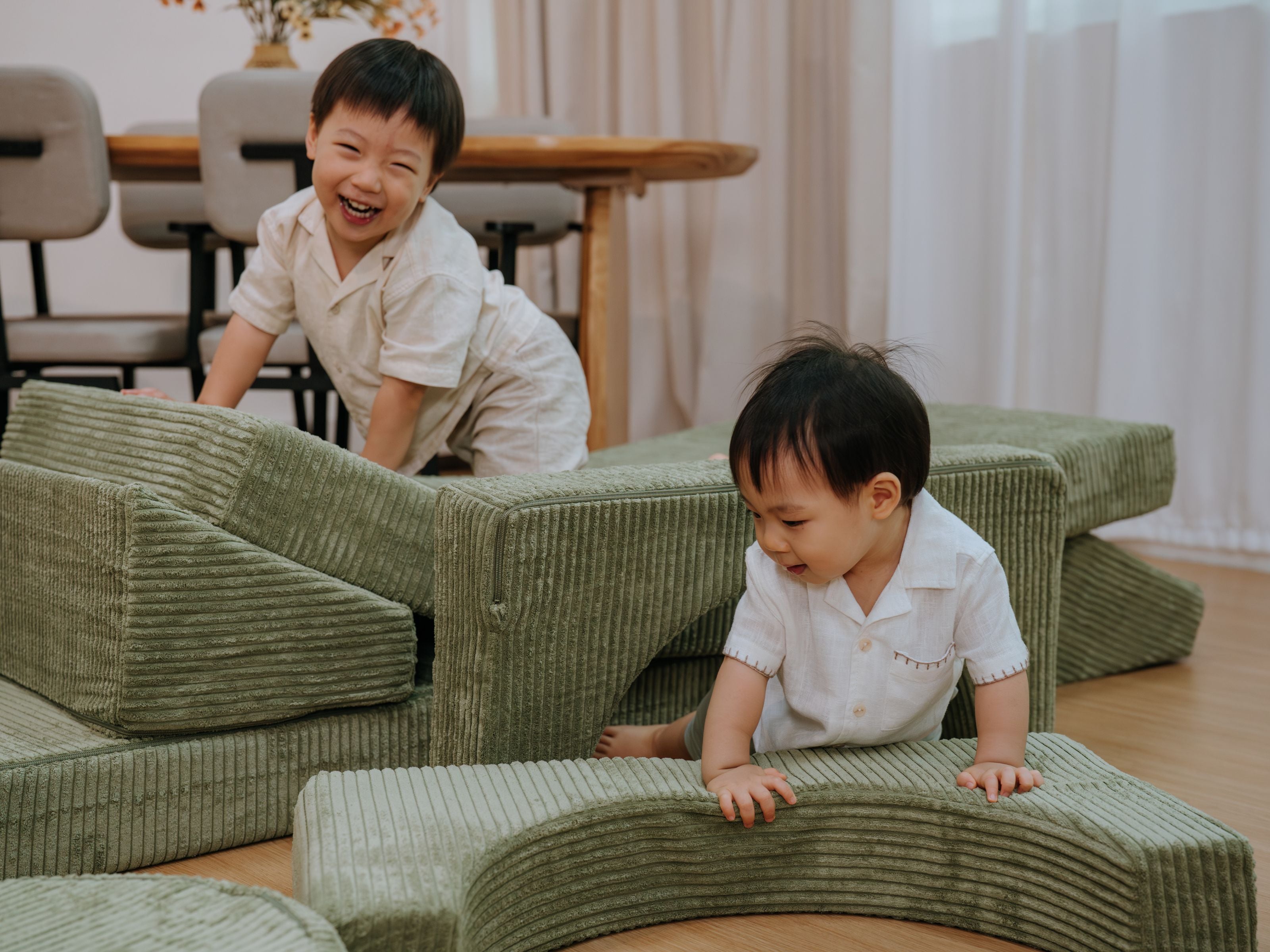 Two toddlers happily crawling across the pieces of the Lollibly Wonderstack Play Sofa