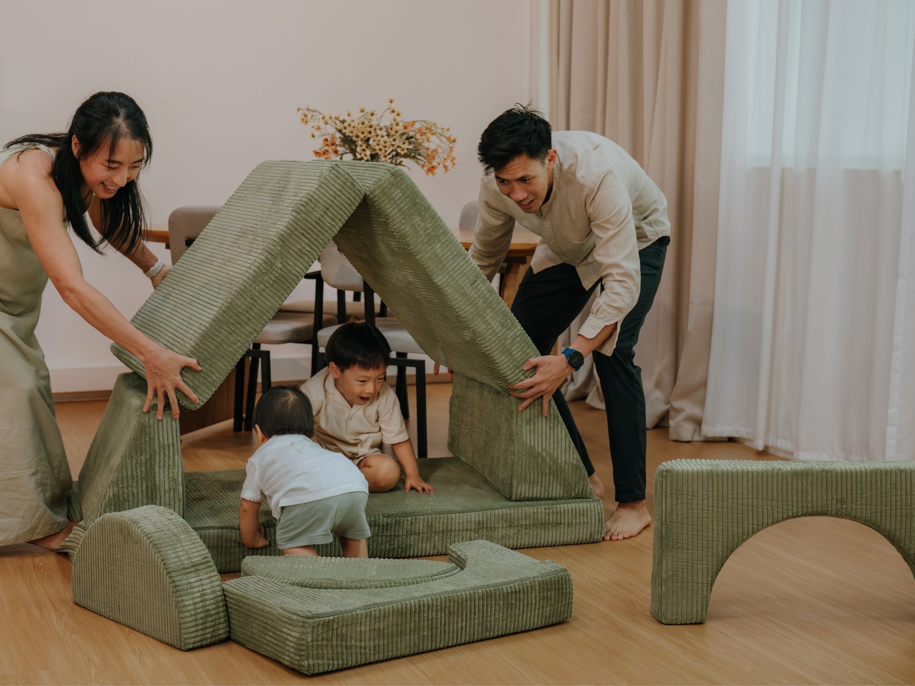 Mum and dad building up a tent configuration with the pieces of the Lollibly Wonderstack Play Sofa for their kids to play with