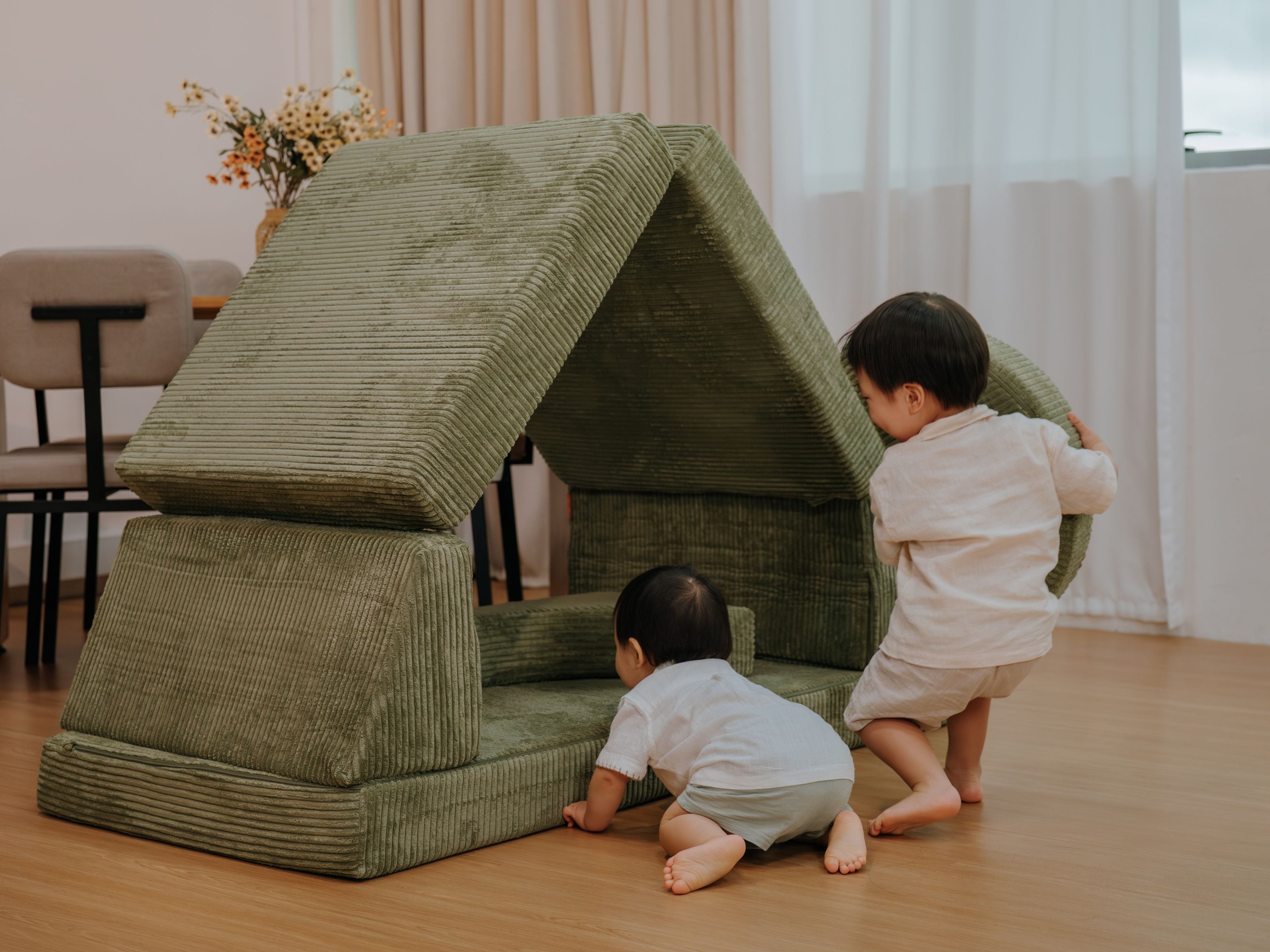 Two toddlers playing with the Lollibly Wonderstack Play Sofa pieces with one of them crawling towards it