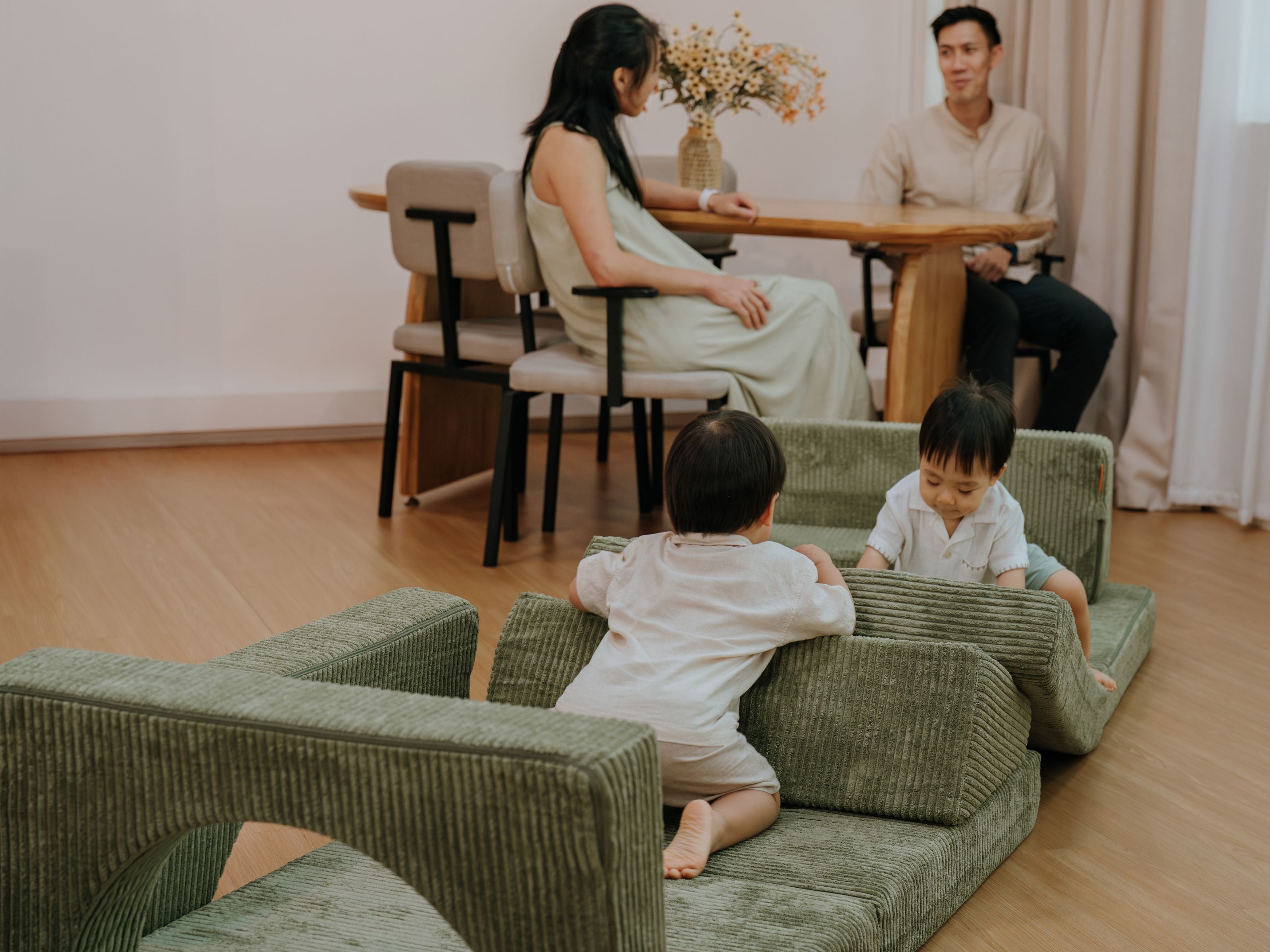 Two brother having fun on an obstacle course made from the Lollibly Wonderstack play sofa as their parents sit nearby