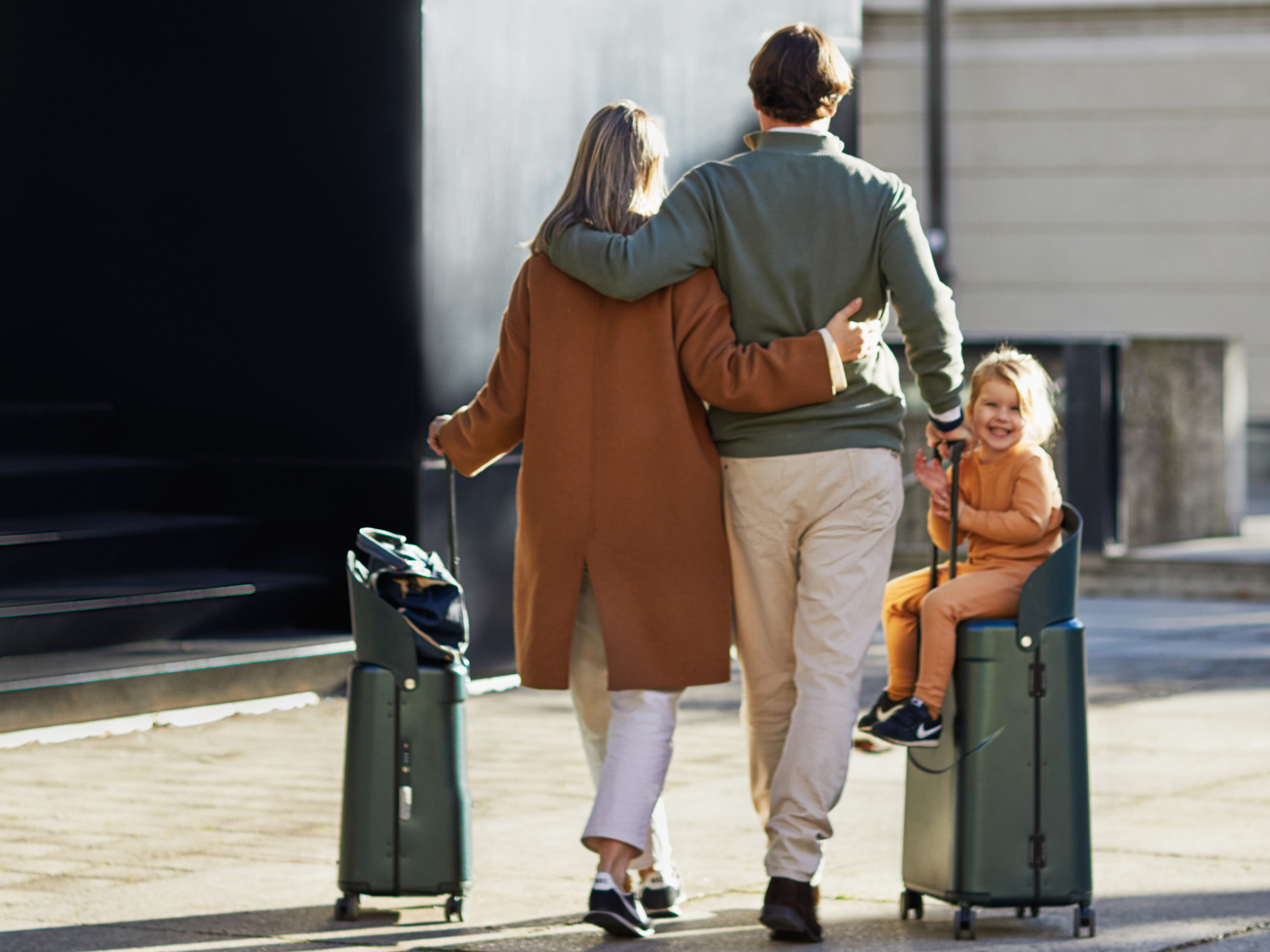 parents pushing little girl on miamily carry on luggage