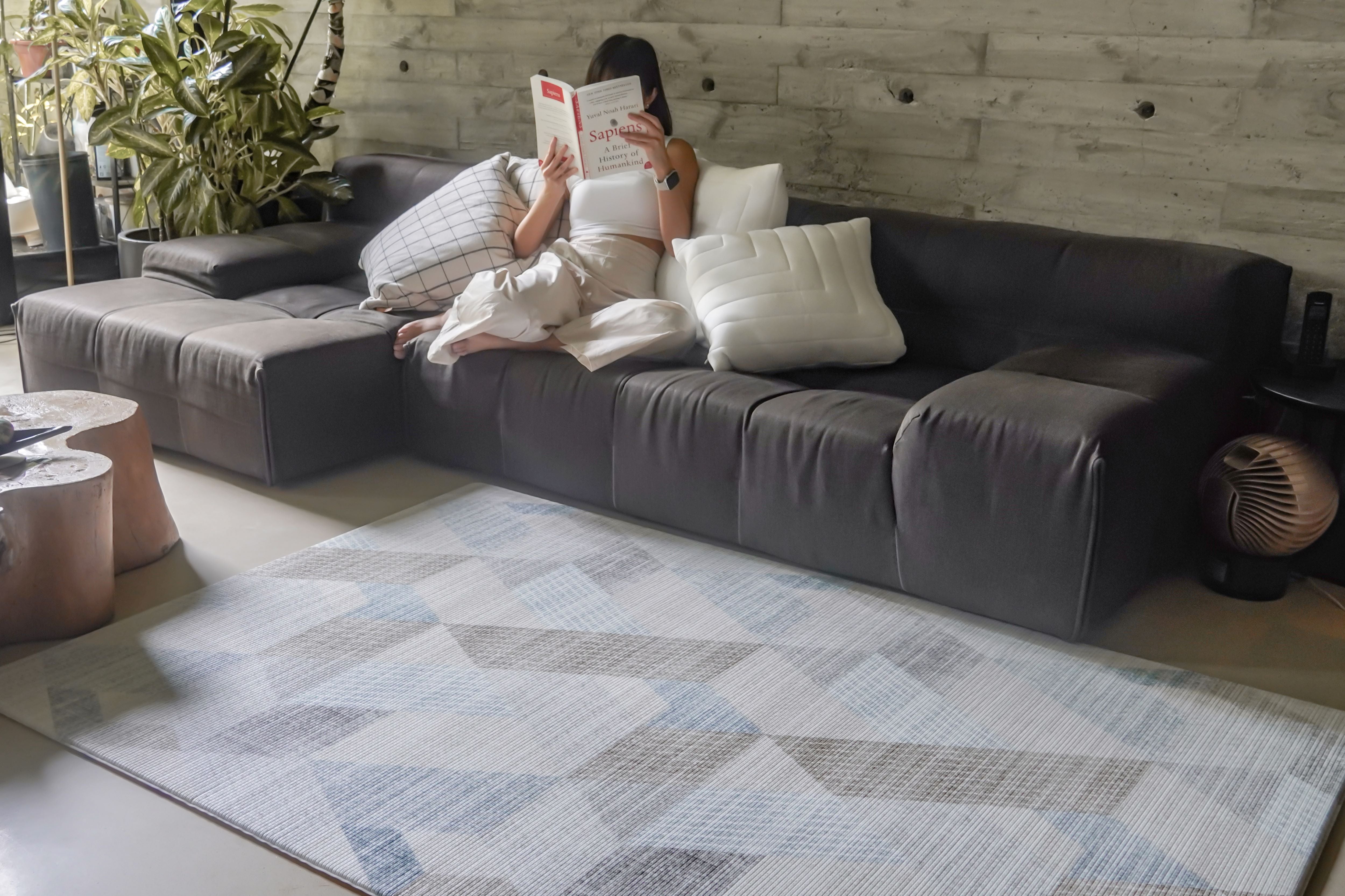 lady reading on couch with lollibly snow dune play mat laid on floor