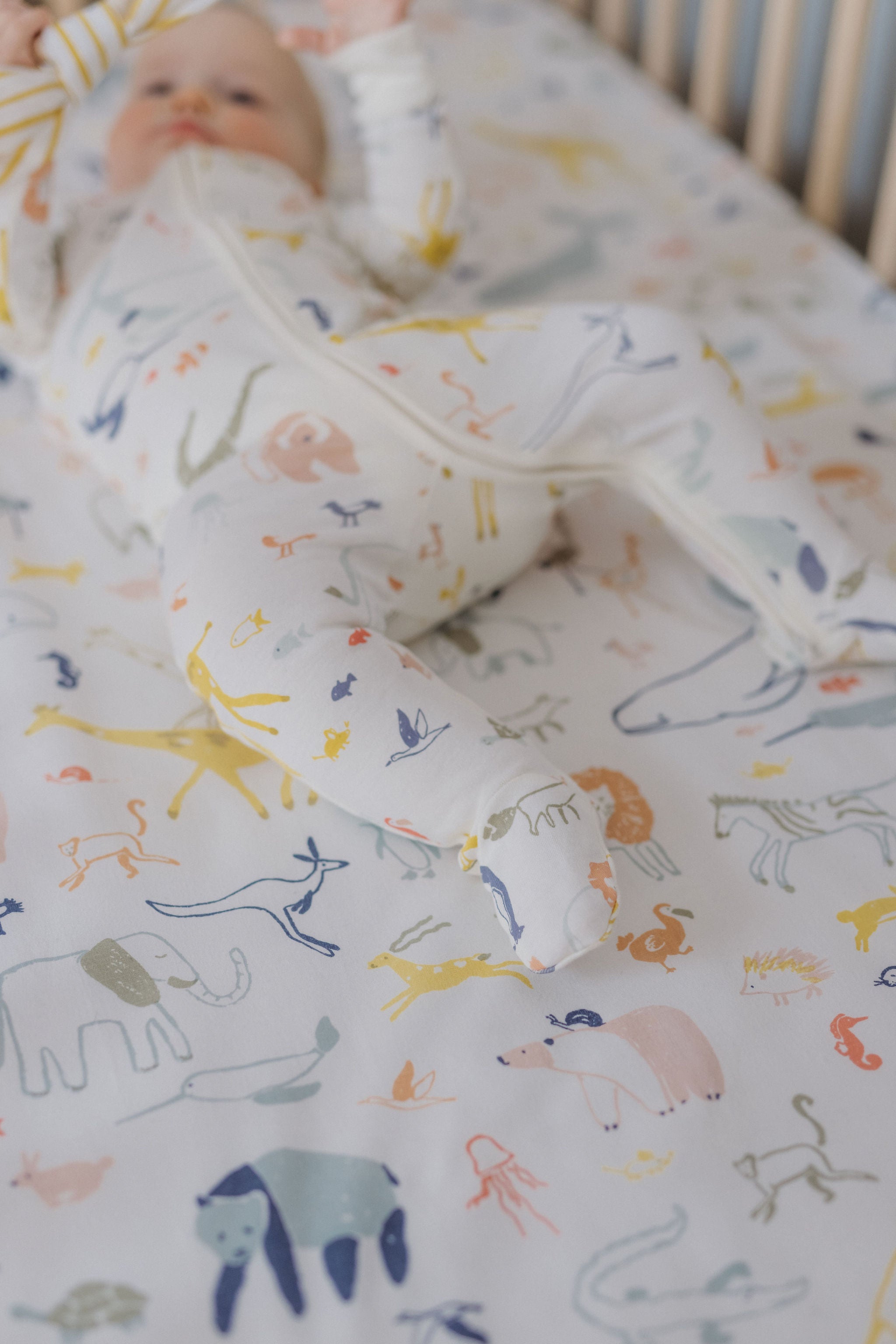 baby lying on crib mattress with pehr into the wild crib sheet