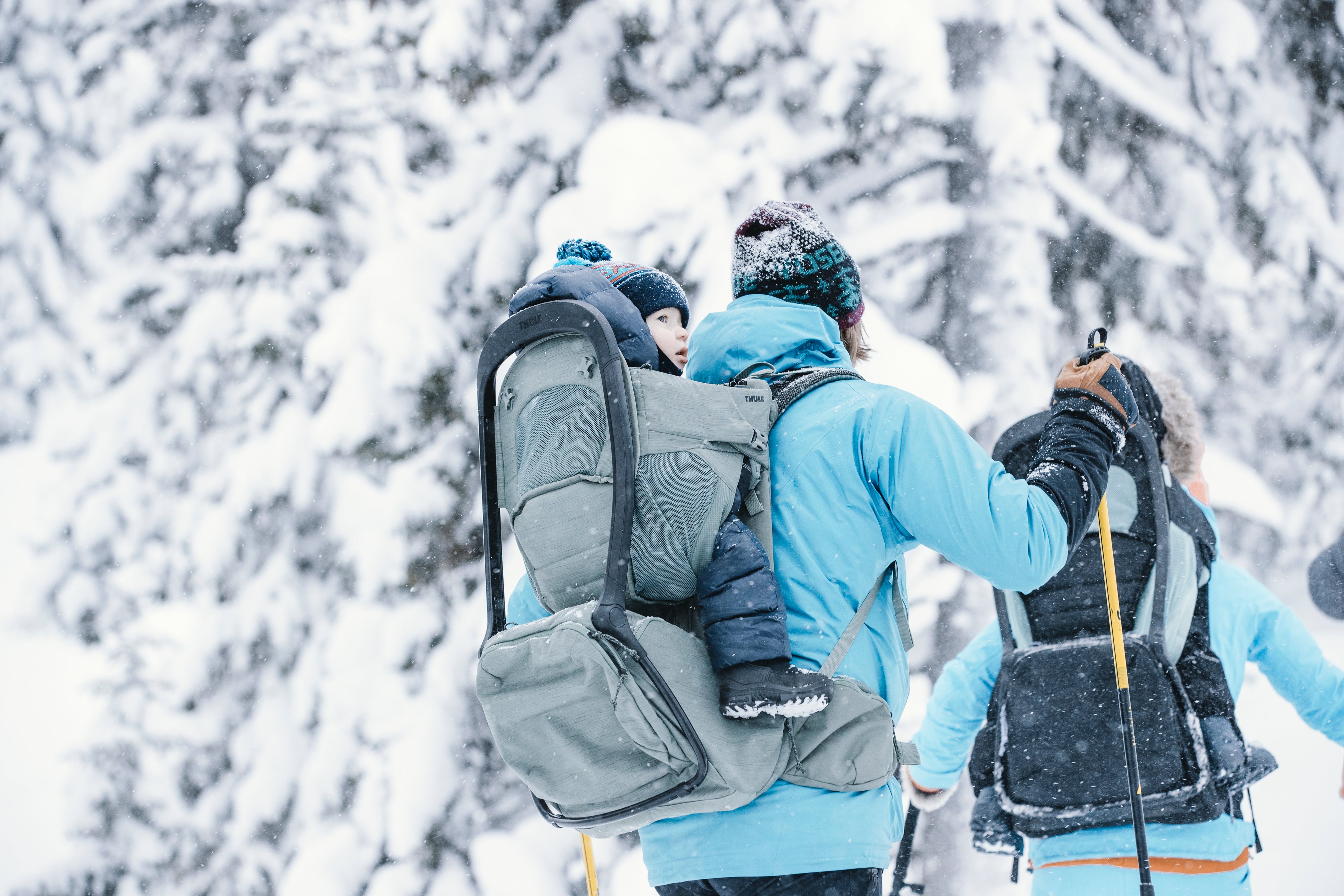 Parents carrying children in Thule Child Carrier Backpack Sapling while hiking in the snow nature glacier