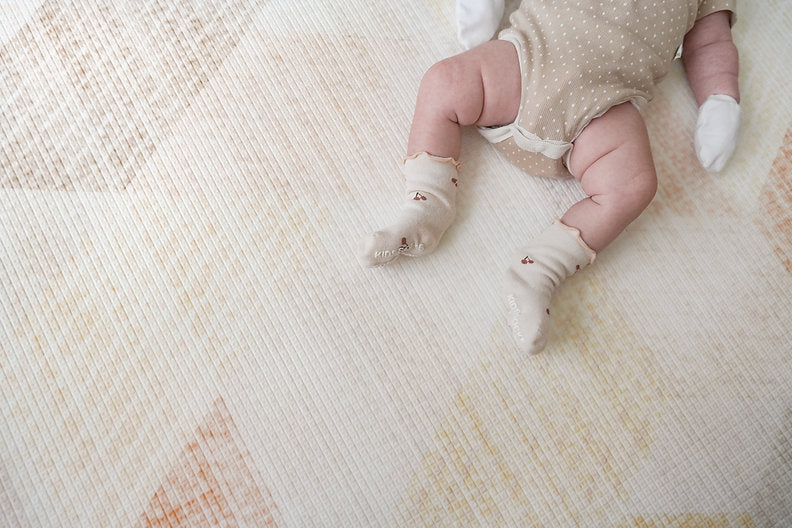 baby legs resting on lollibly sand dune playmat