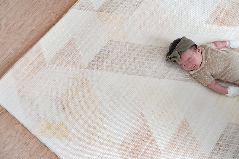 happy baby lying on lollibly sand dune playmat
