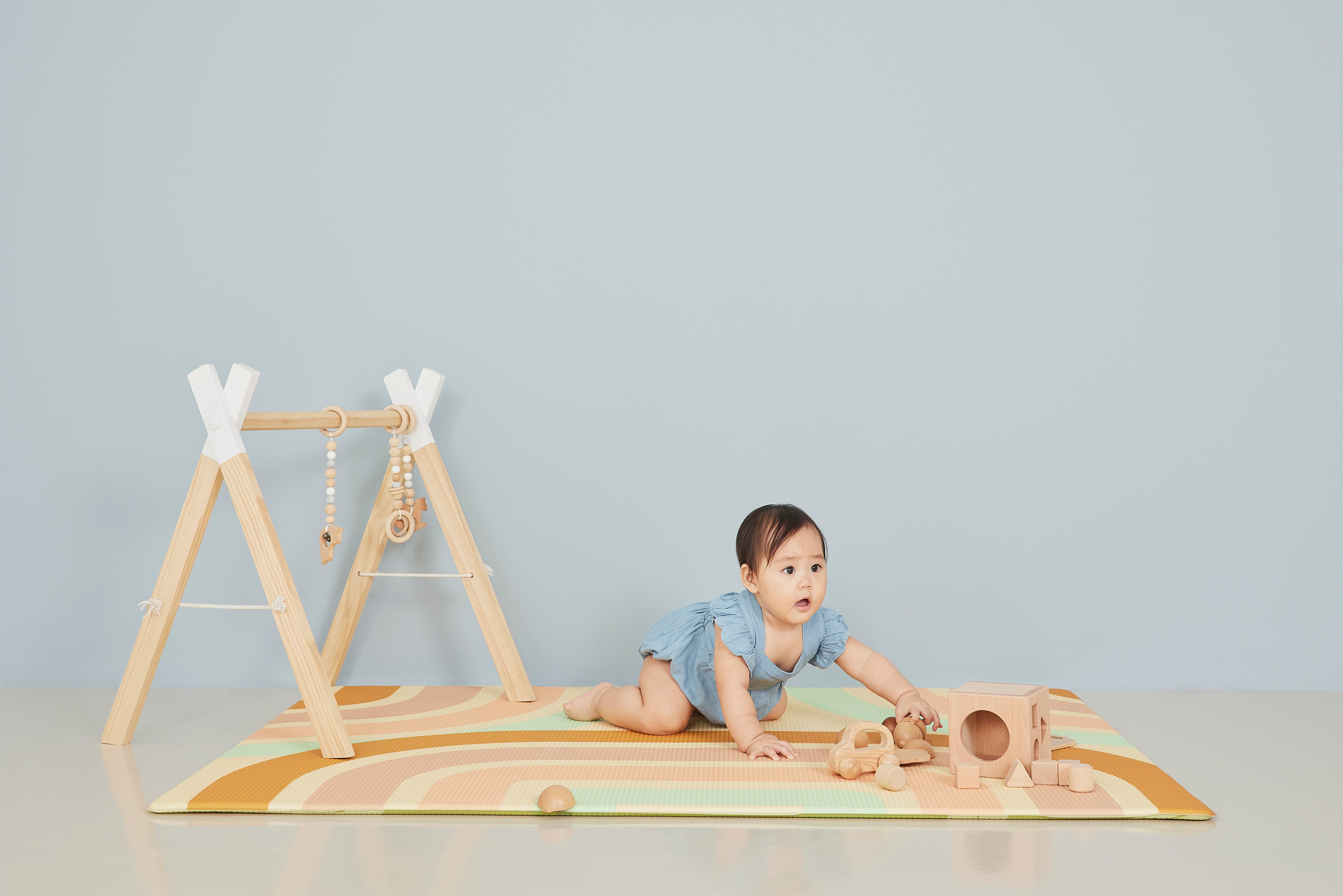 baby girl playing with wooden blocks on lollibly holiday play mat