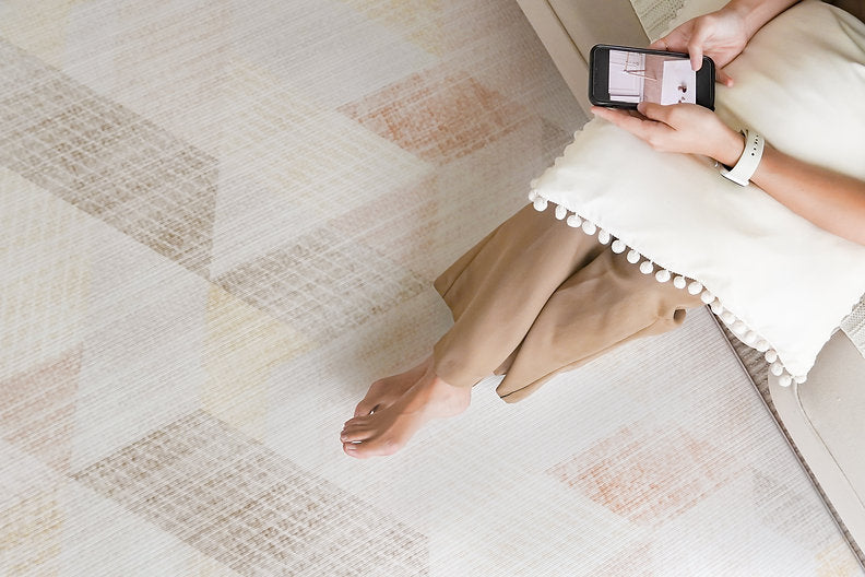 lady sitting on couch using phone and feet resting on lollibly sand duneplaymat