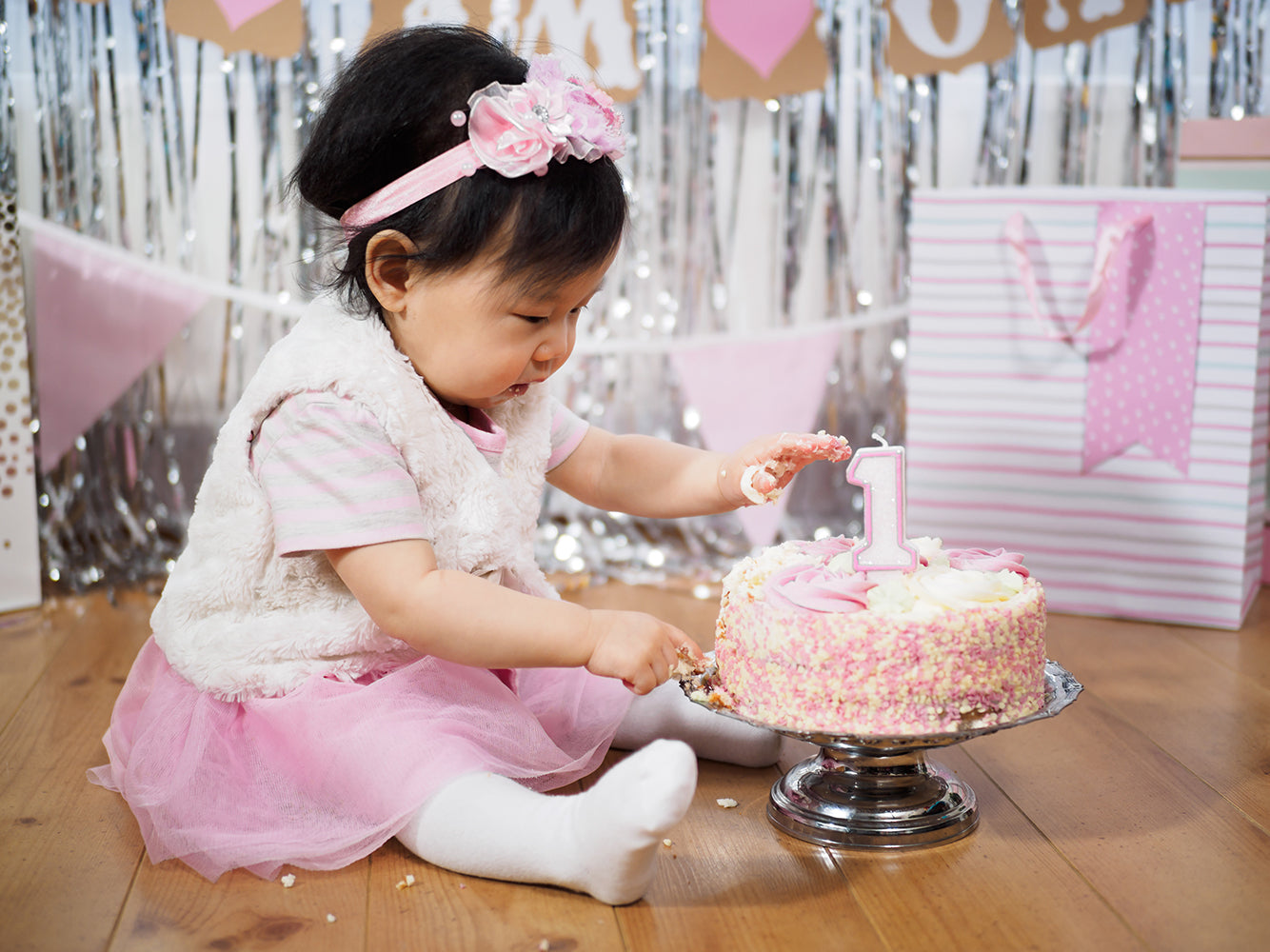 Baby Girl sitting on the floor with a cake and Celebrating First Birthday