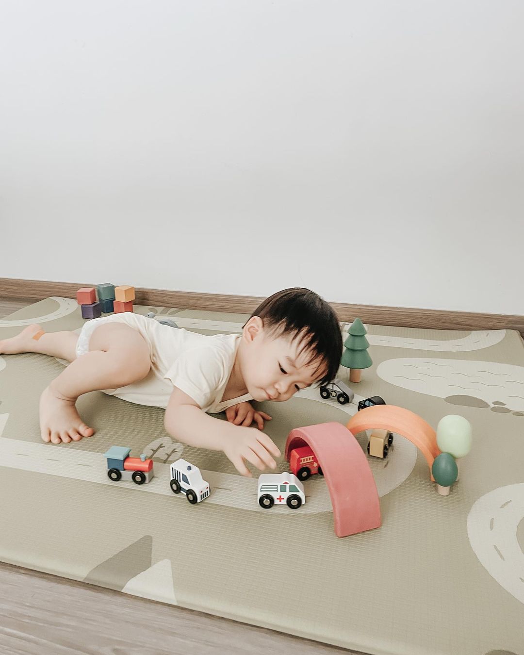 child playing with wooden toy cars on Lollibly playmat
