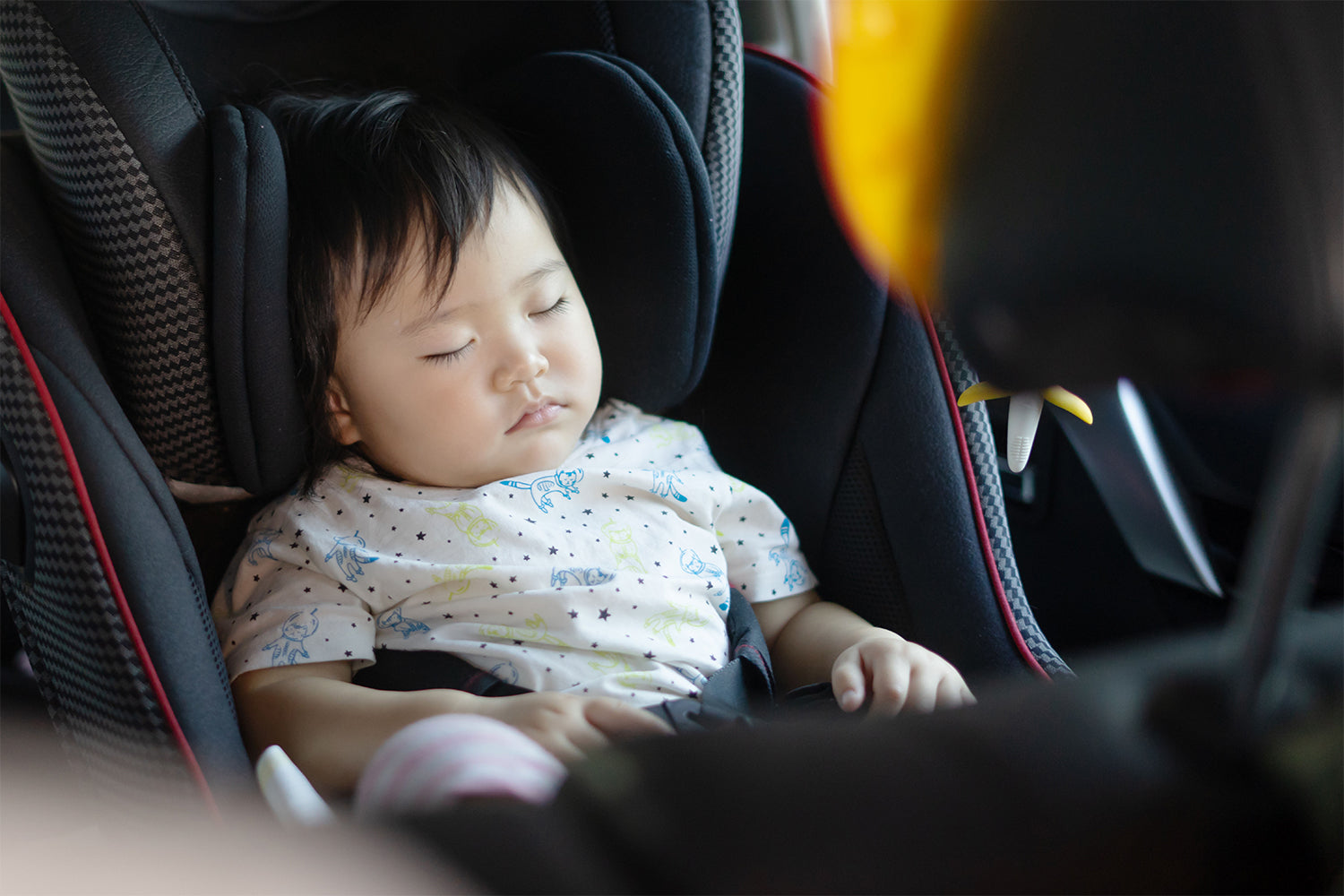 baby boy sleeping on her car seat at the back of the car