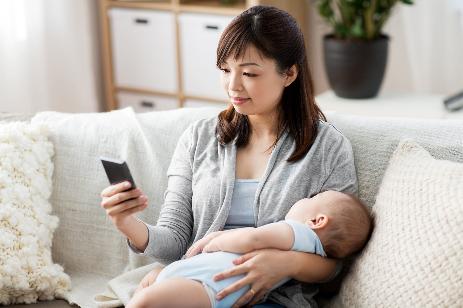 mother checking on a phone app while taking care of baby