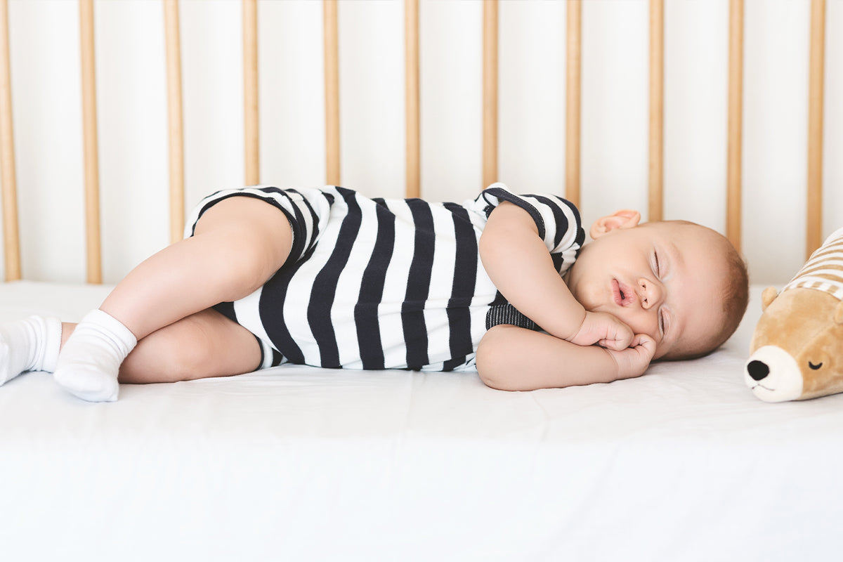 Adorable newborn boy napping on his side in crib