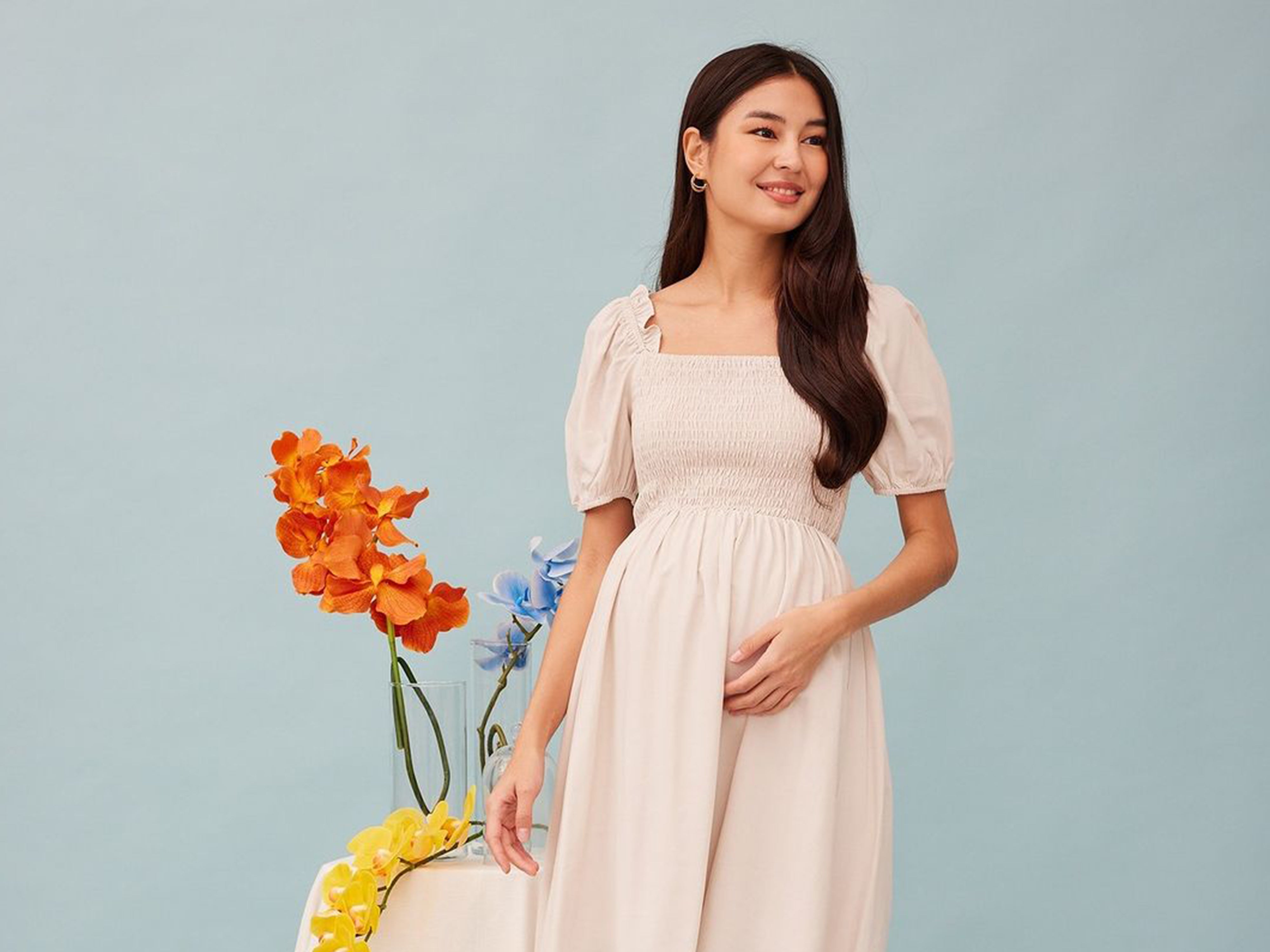 pregnant mum wearing maternity dress with table of flowers in the background