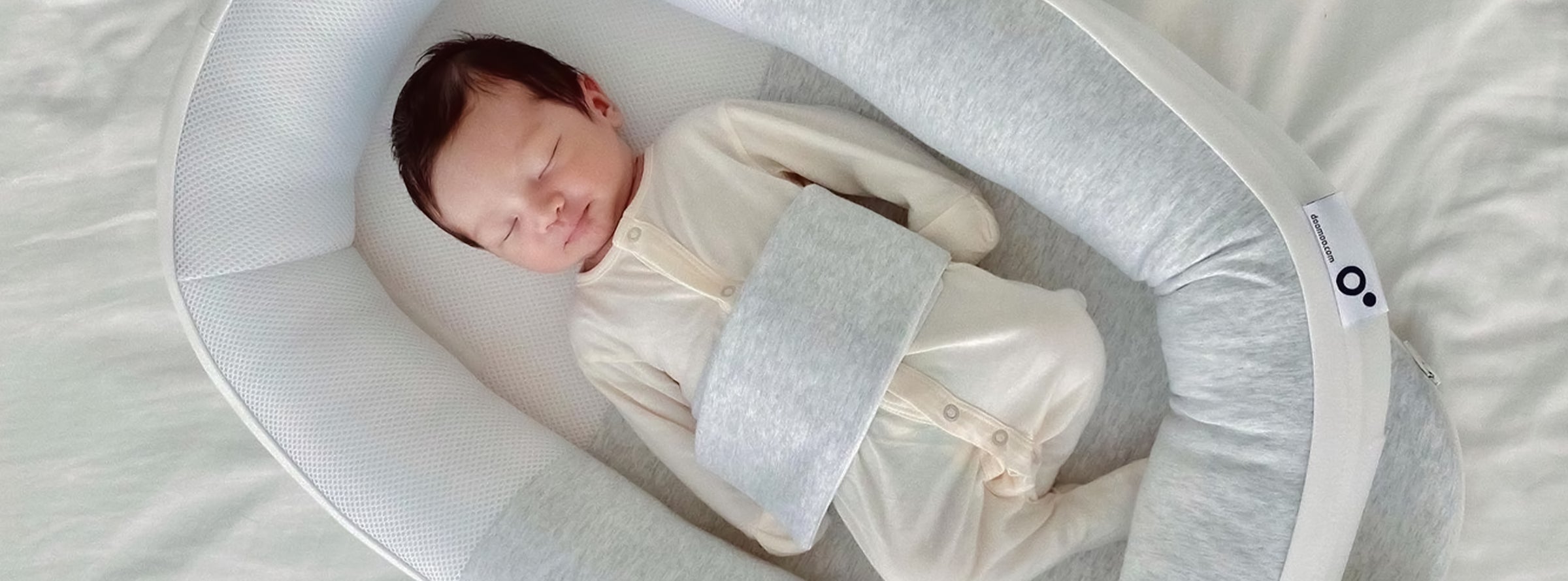 newborn sleeping in baby nest doomoo cocoon sleep positioner