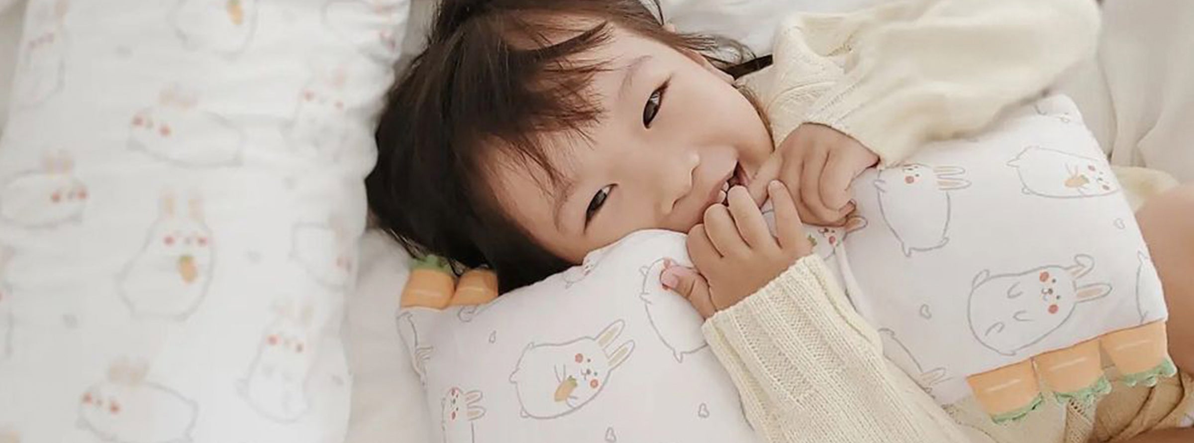 toddler hugging cho pillow in bed smiling laughing