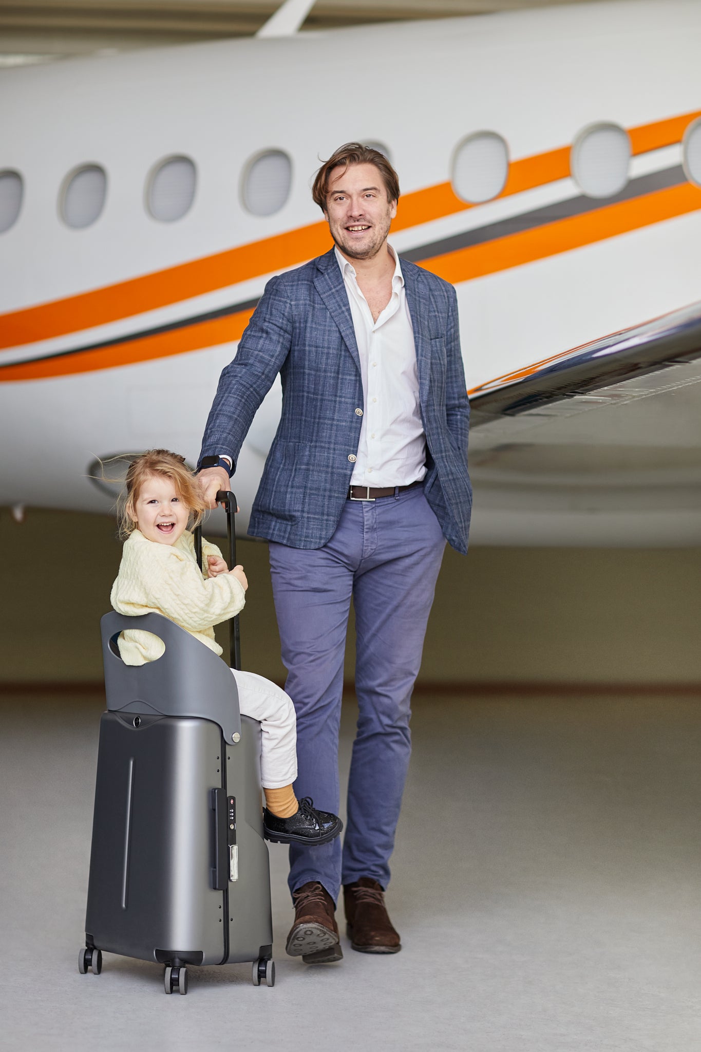 father with a little daughter sitting on miamily grey luggage