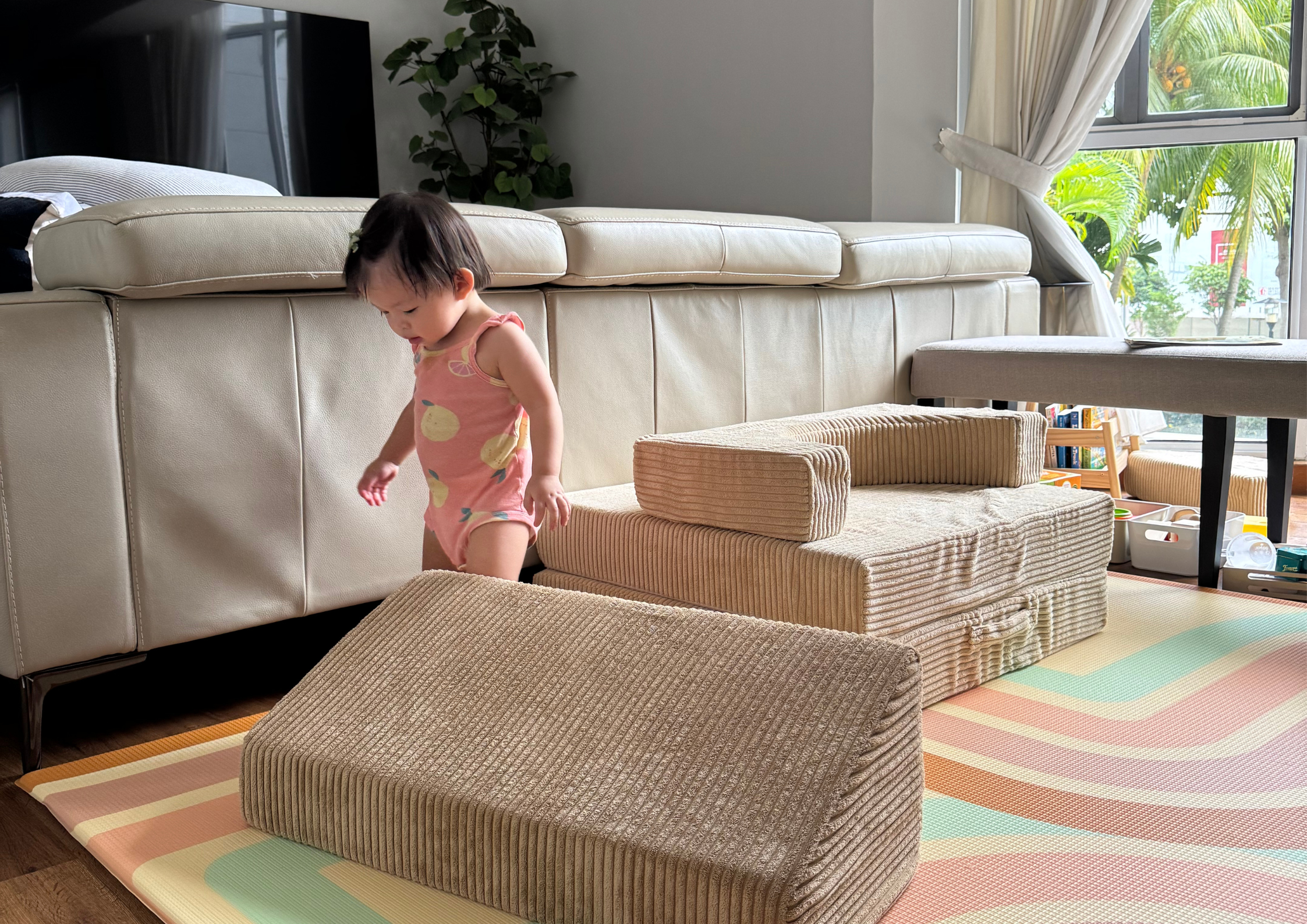 Toddler playing with Wonderstack play sofa on a baby play mat in a living room.
