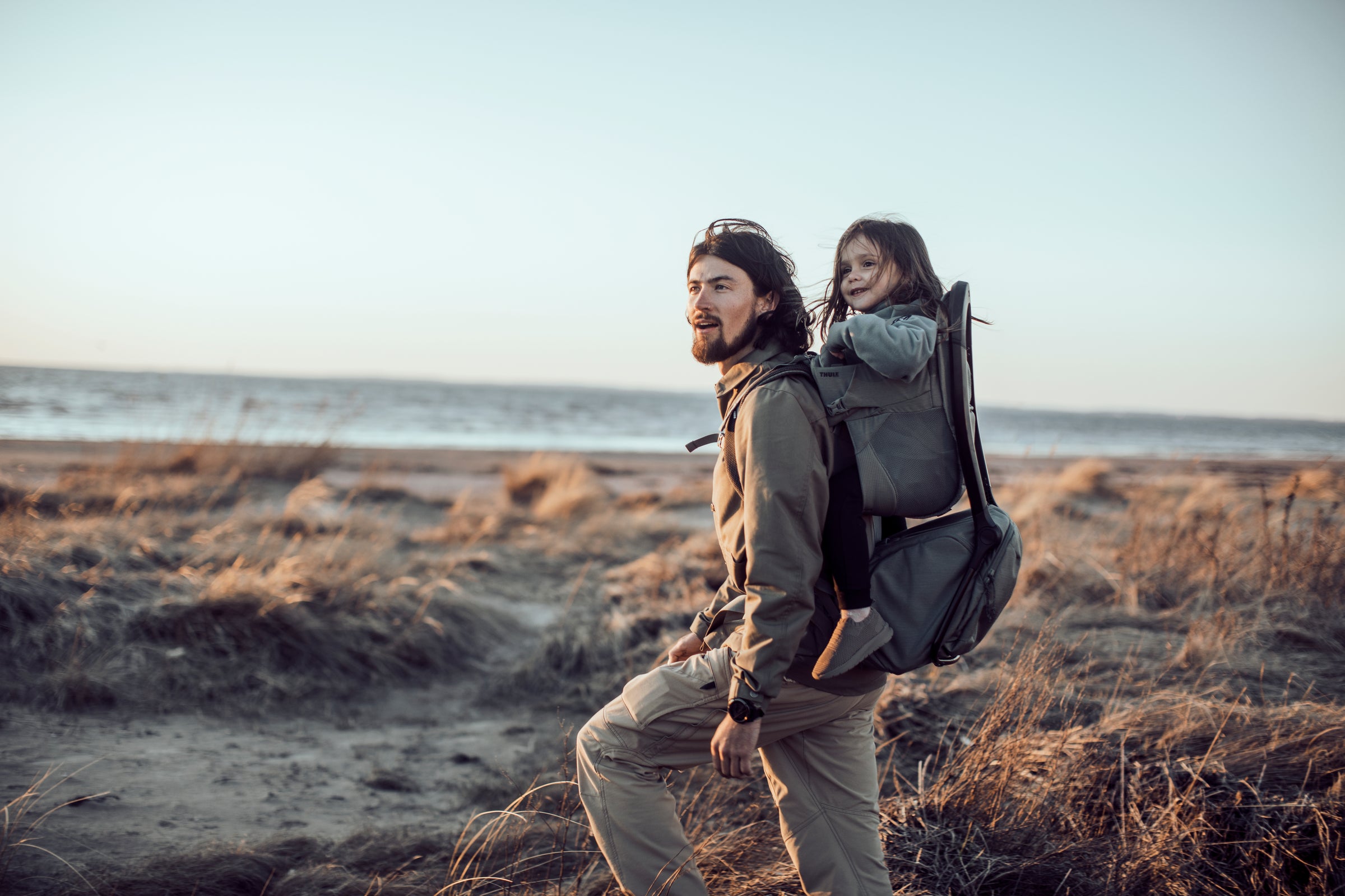 father carrying toddler in backpack carrier thule sapling outdoor hike