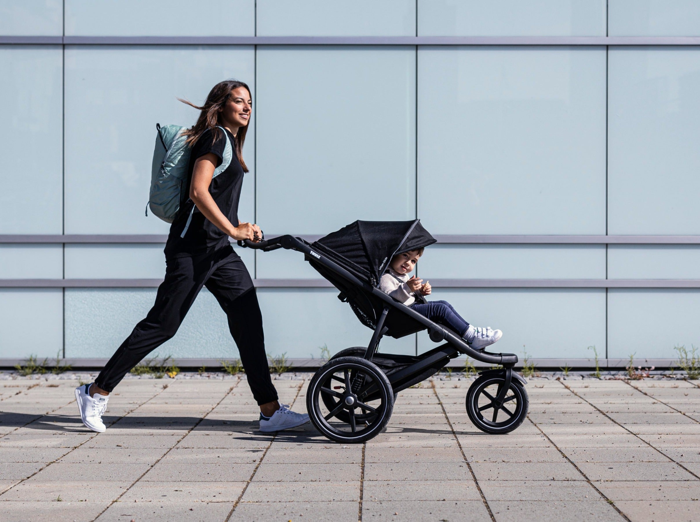 Mum pushing child in Thule Urban Glide 2 All-Terrain Jogging Stroller Black