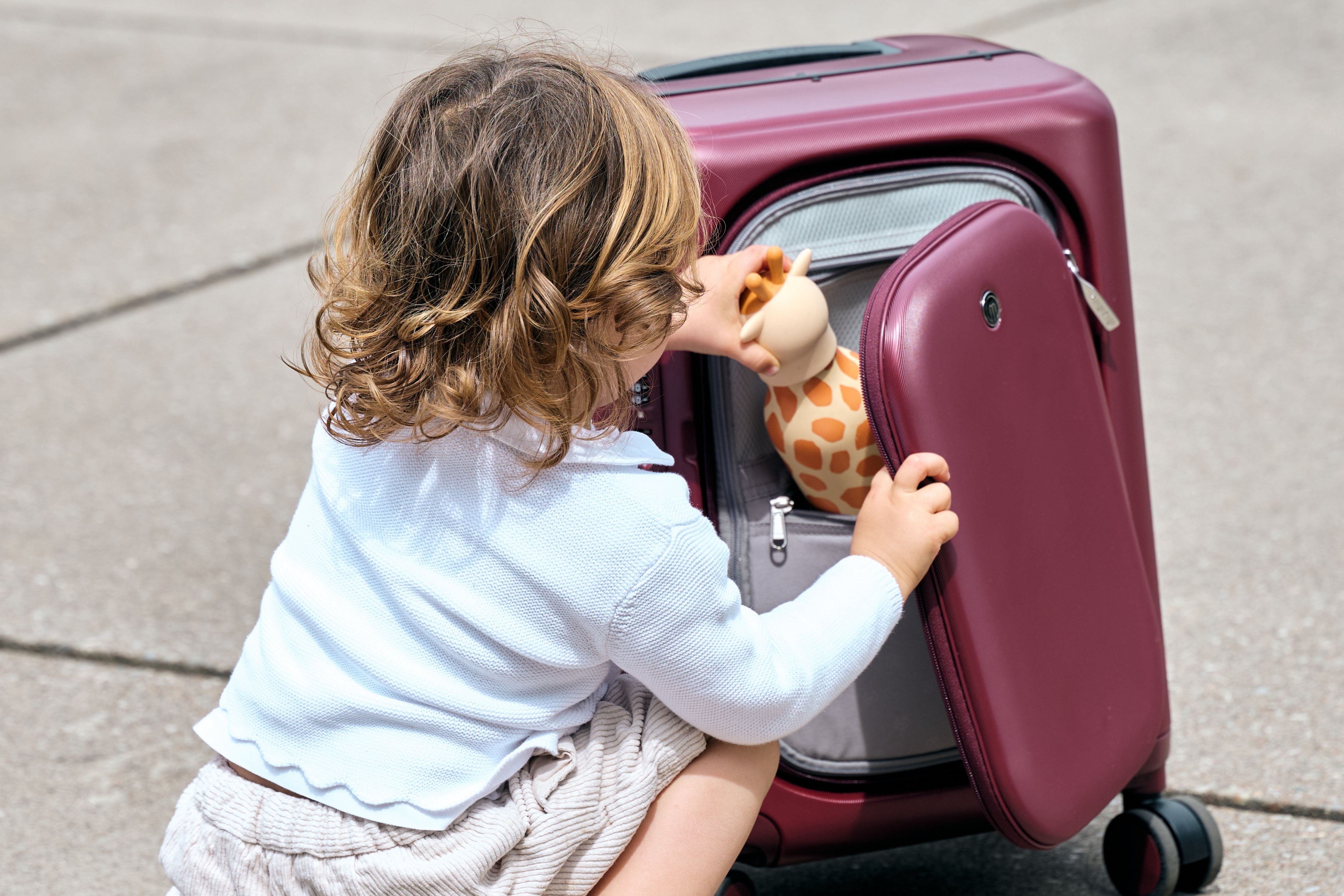 A toddler opening the front compartment of the MiaMily Carry On Plus 18” Luggage 