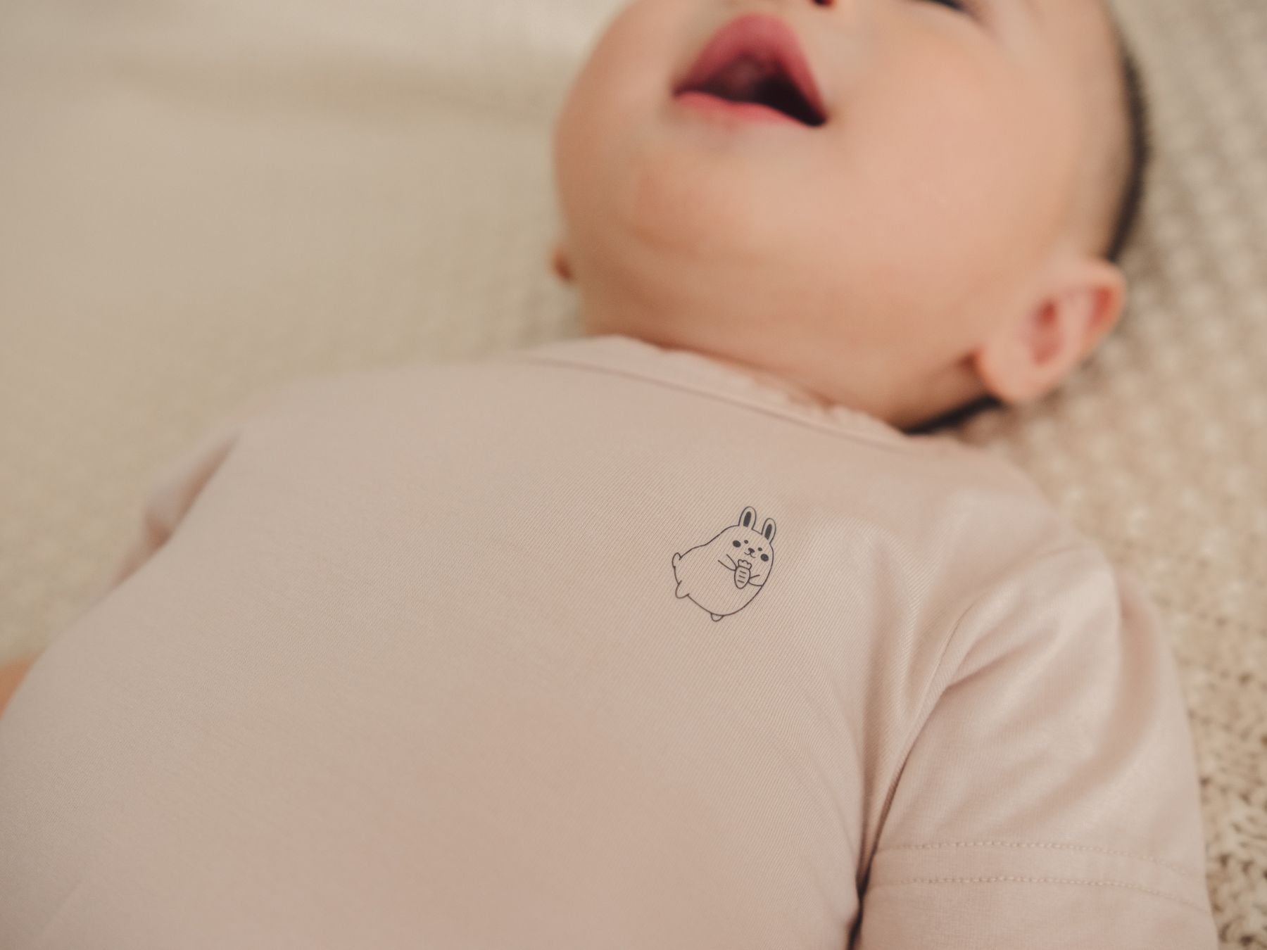 Close-up of a baby wearing a beige onesie, highlighting the design details