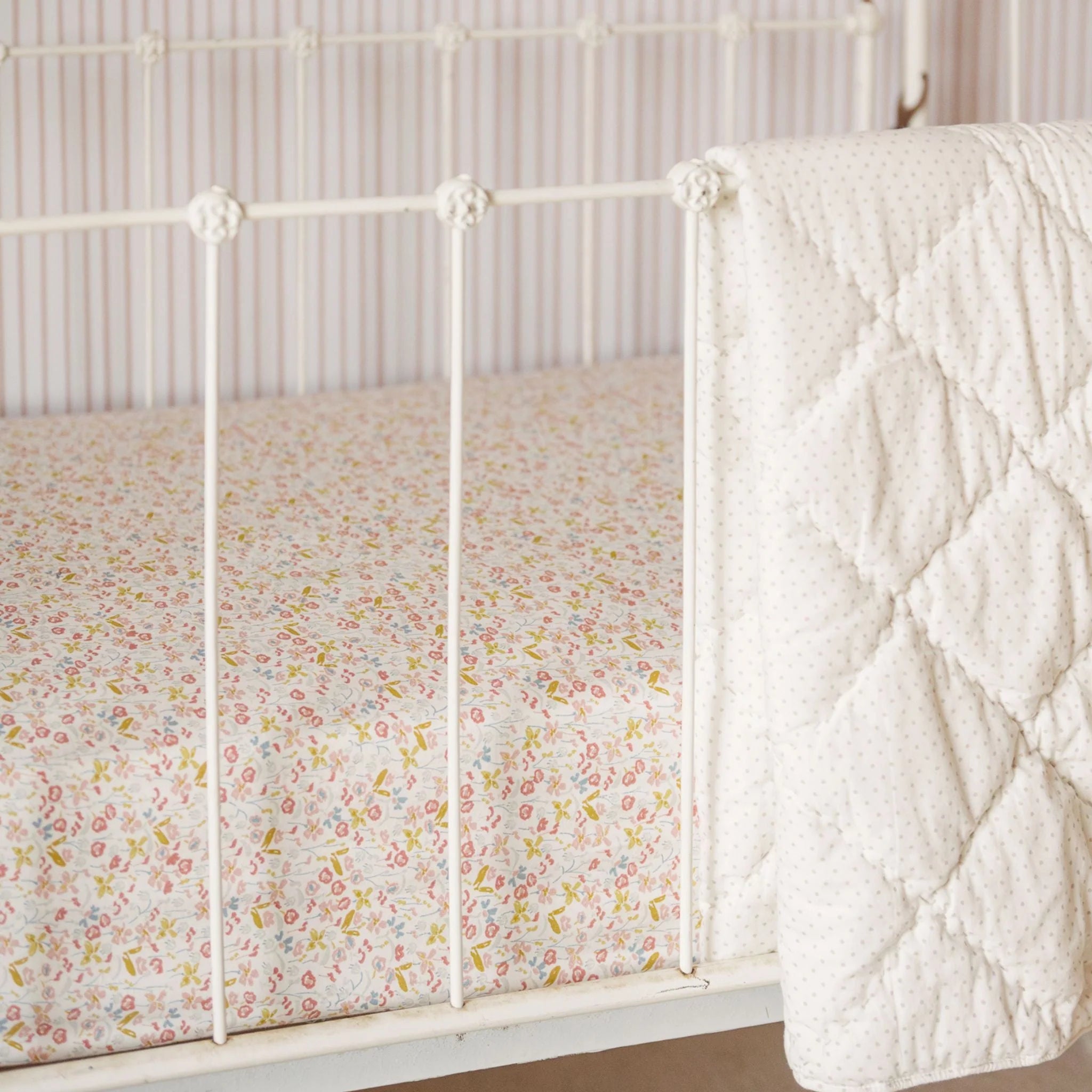 Crib with floral sheet and textured white blanket