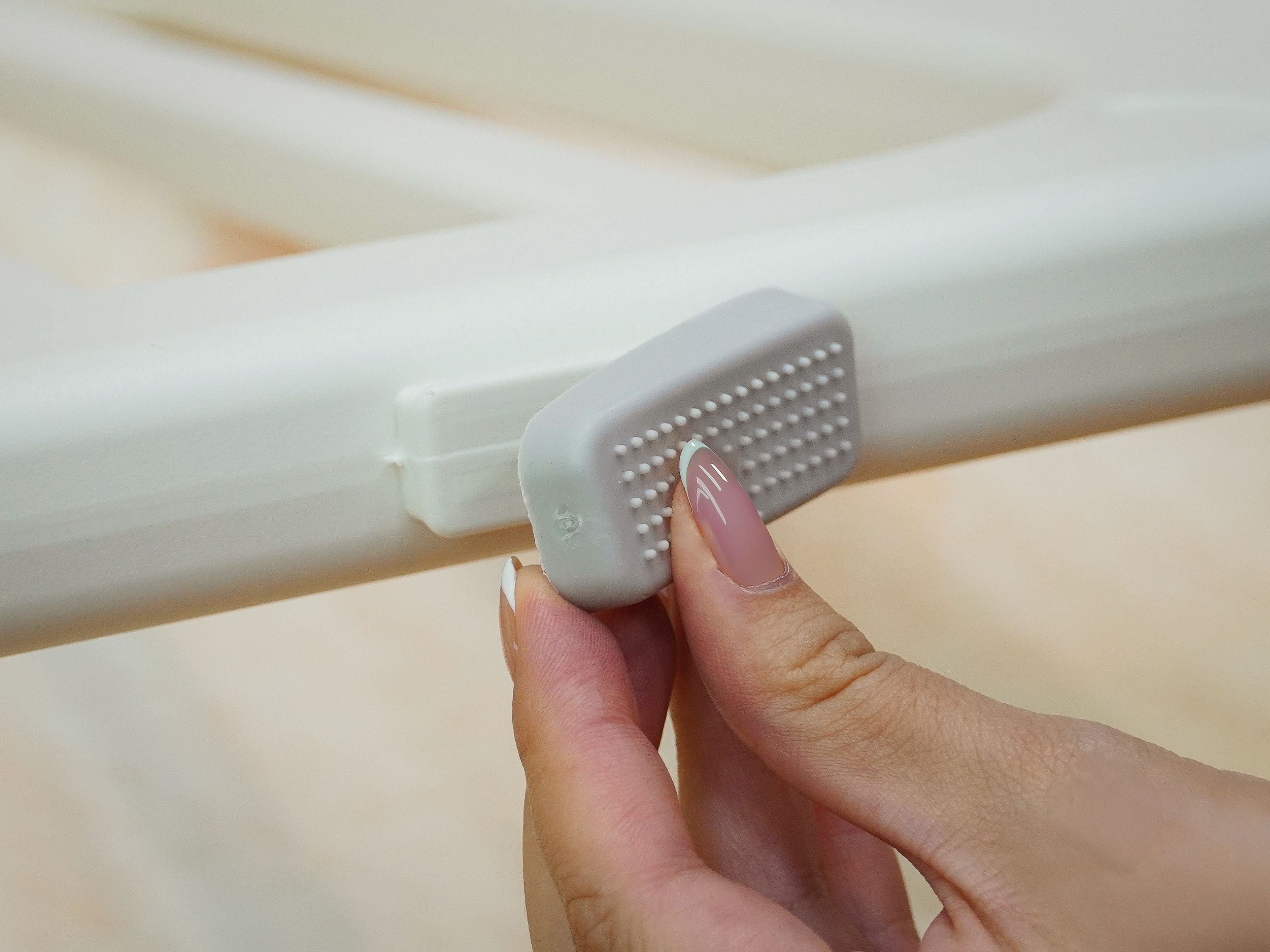 Close-up of hand putting on the anti-slip pad of the Lollibly Meadow Playpen