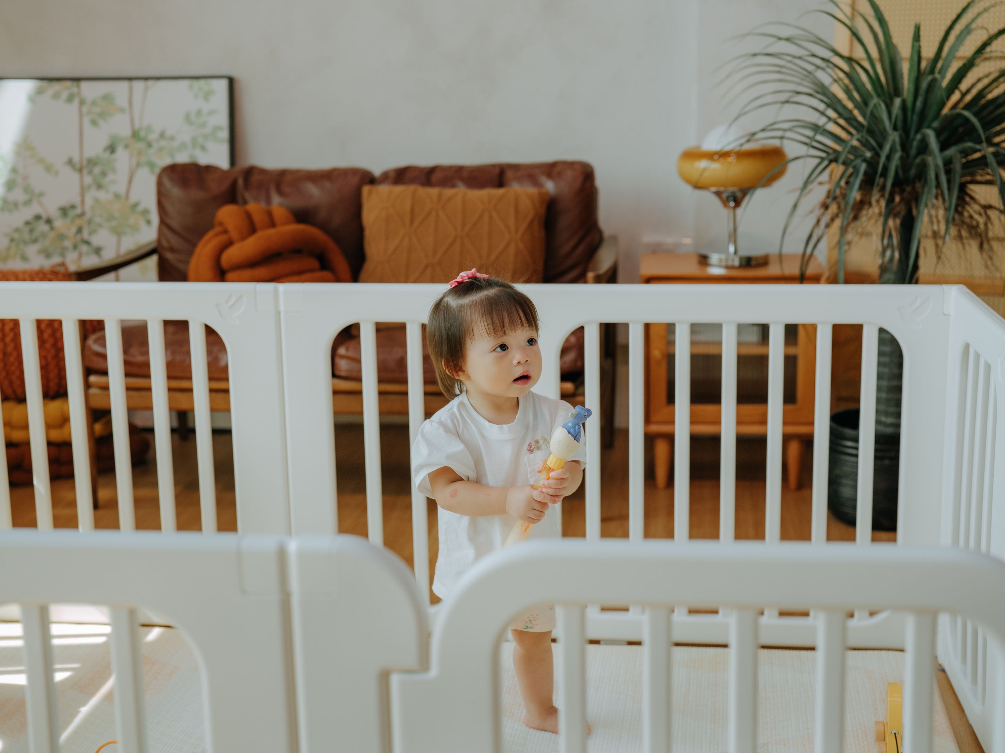 Toddler standing in the middle of the Lollibly Meadow playpen, placed in a cosy living room
