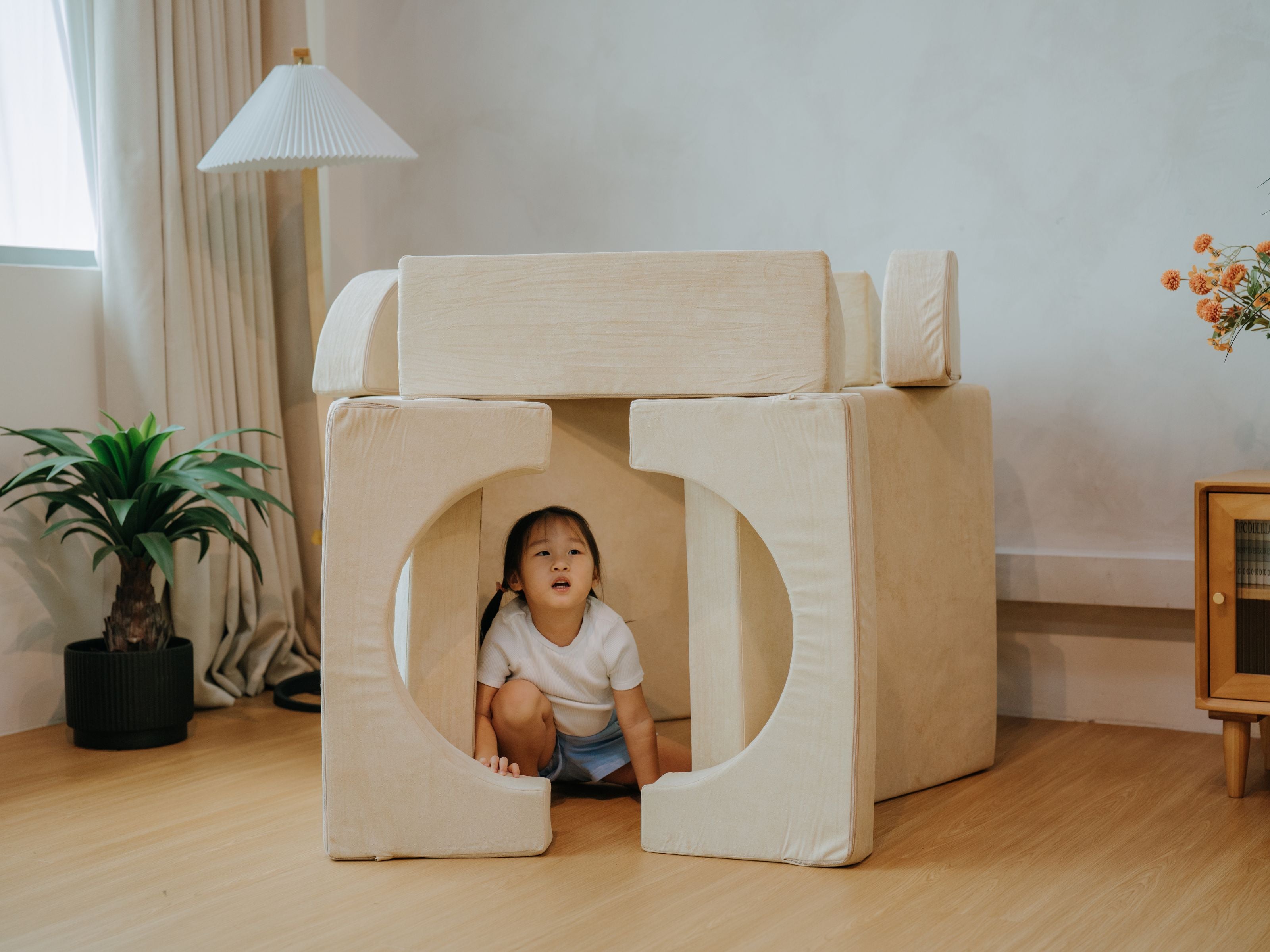 Child squatting in the middle of a tower configuration she built using pieces from the Lollibly Wonderstack Play Sofa