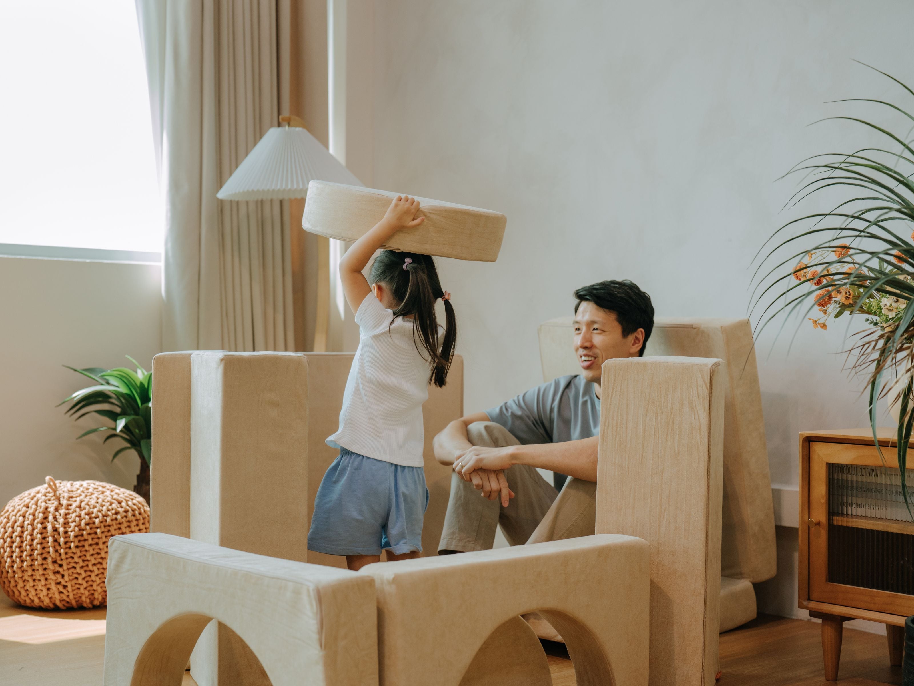 Child moving pieces of the Lollibly Wonderstack Play Sofa while her dad sits and watches her play