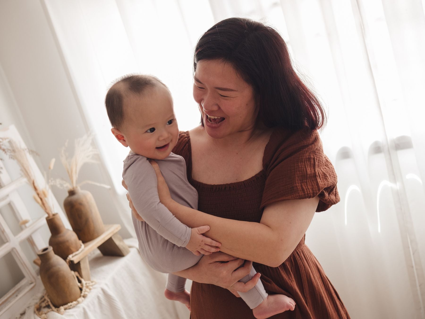 Mother holding her baby in her arms, baby wearing a lavender sleep suit