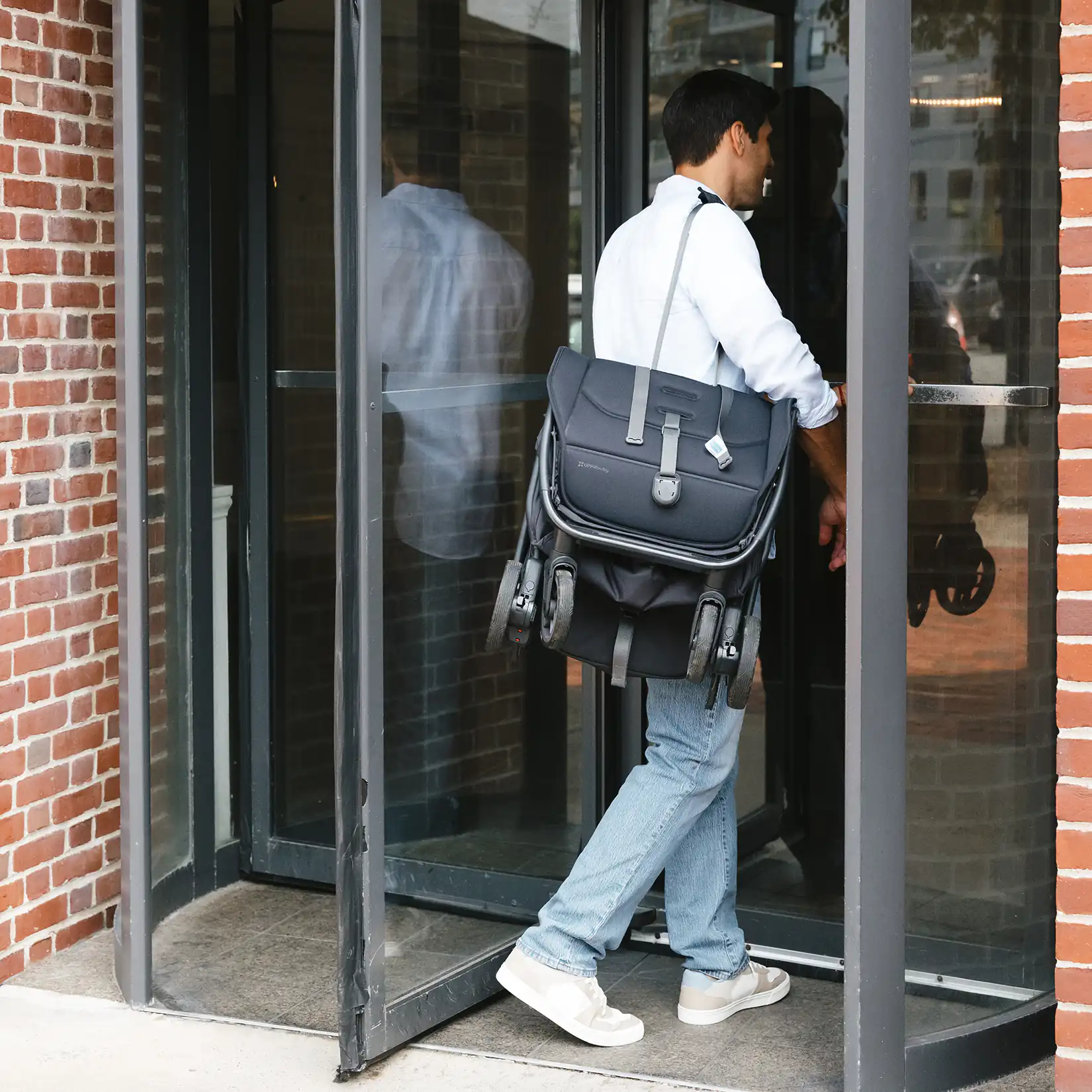 Dad carrying the UPPAbaby Minu V3 Stroller by the shoulder strap #color_jake