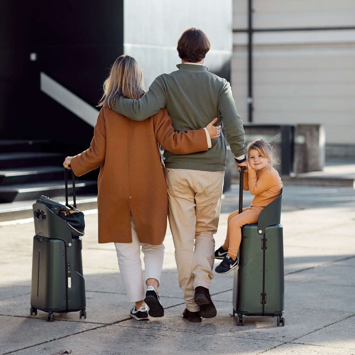 father pushing child on MiaMily luggage while mother rests her bag on her luggage