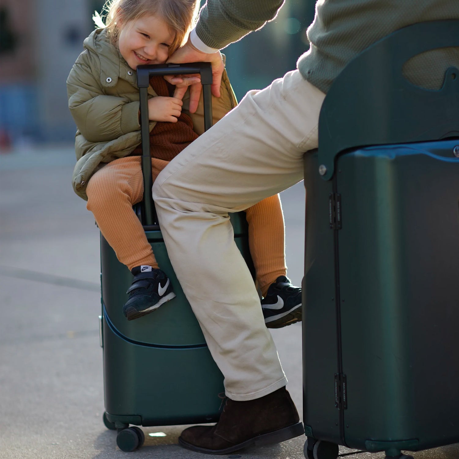 happy child giggling as father tickles her while sitting on luggage