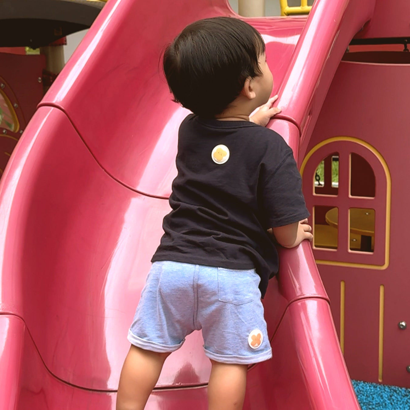 child on playground slide with mosquito repellent patch on shirt and pants