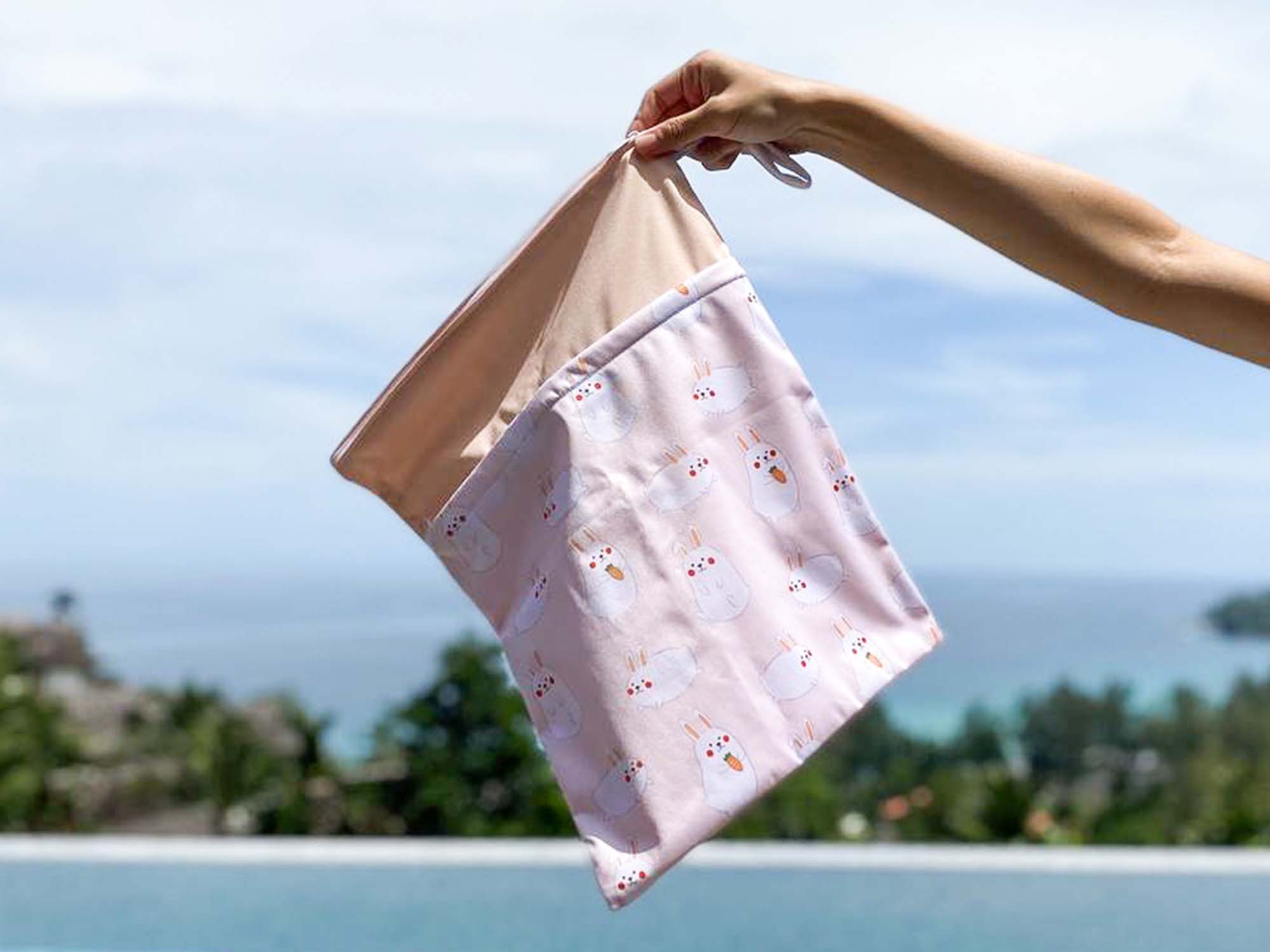 hand holding onto momo peach waterproof wet bag