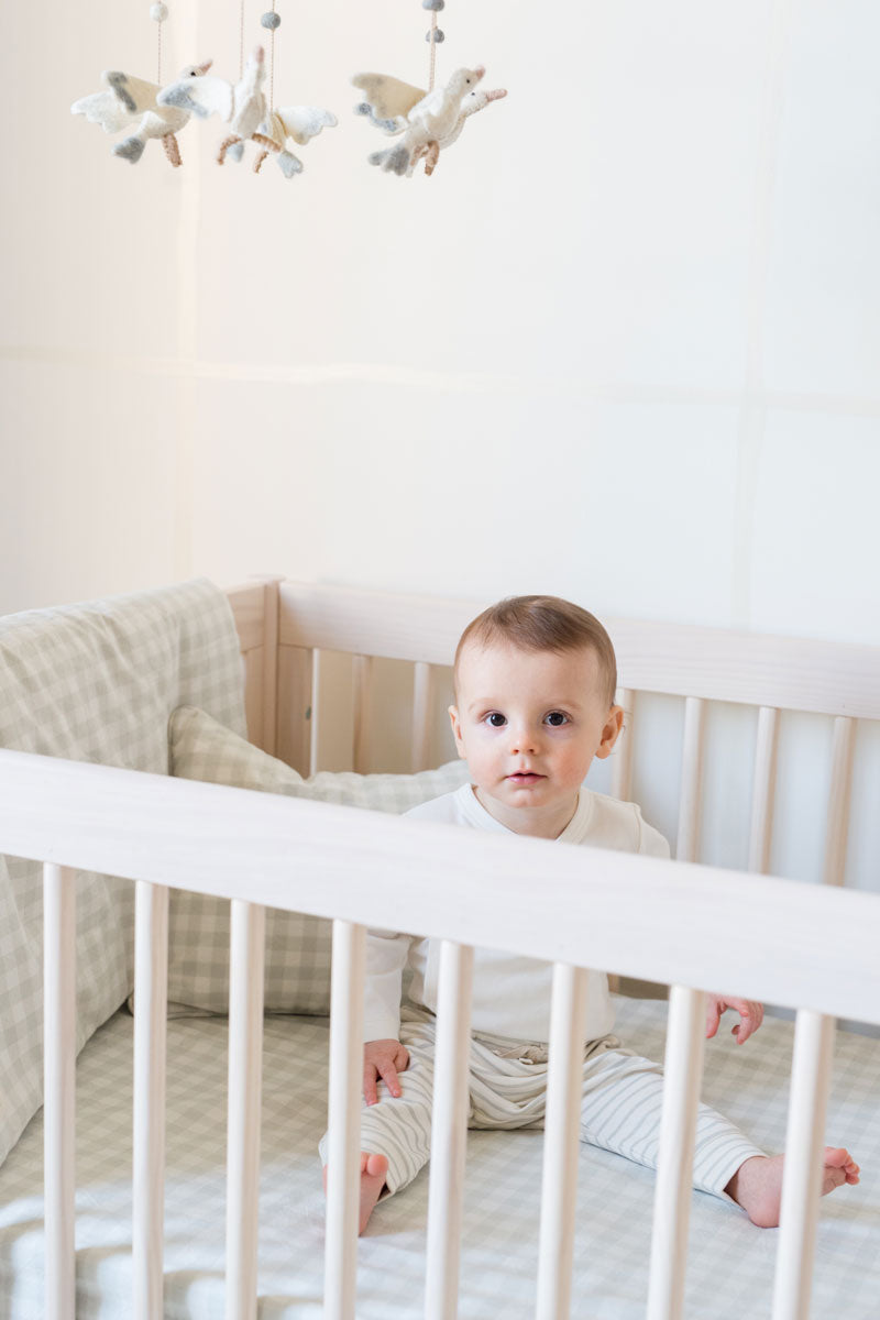 baby boy in crib with pehr checkmate fog bedding