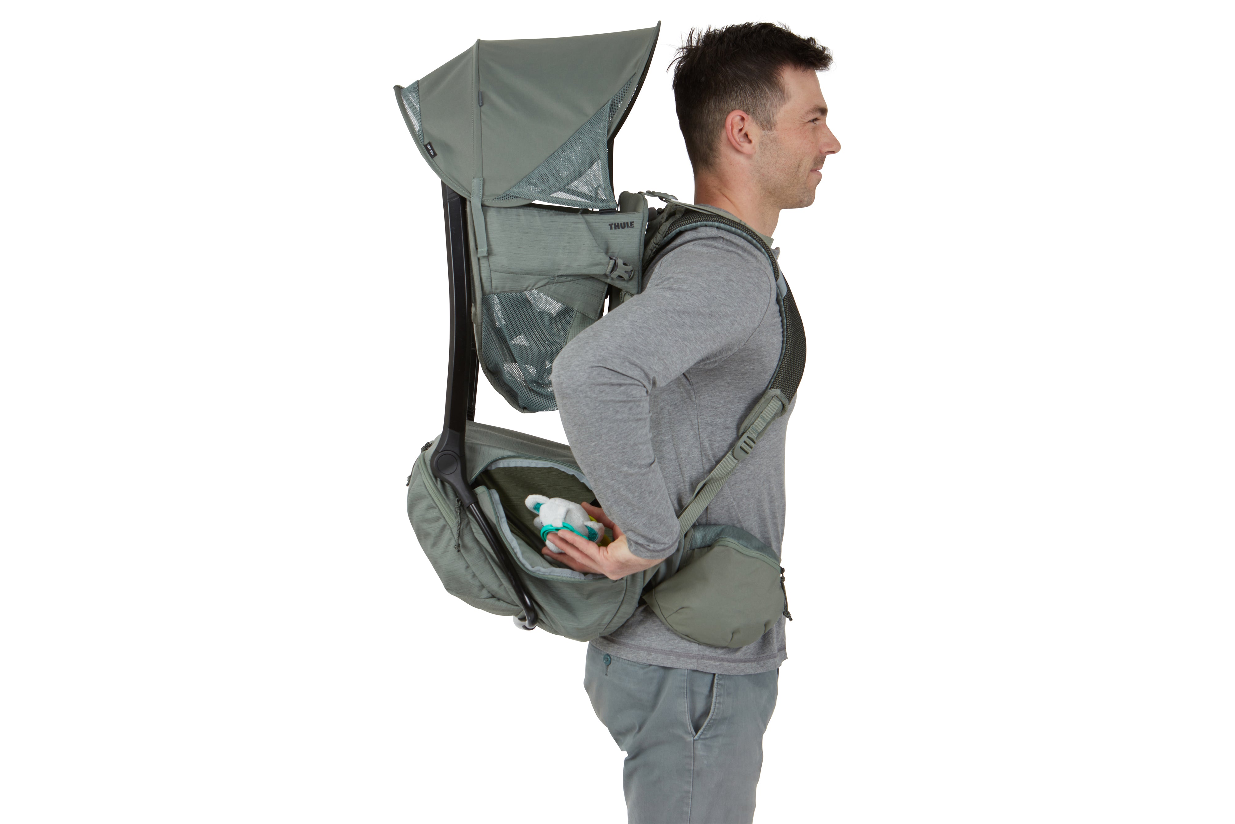 man carrying child carrier backpack and keeping baby toy in extra storage zipper compartment