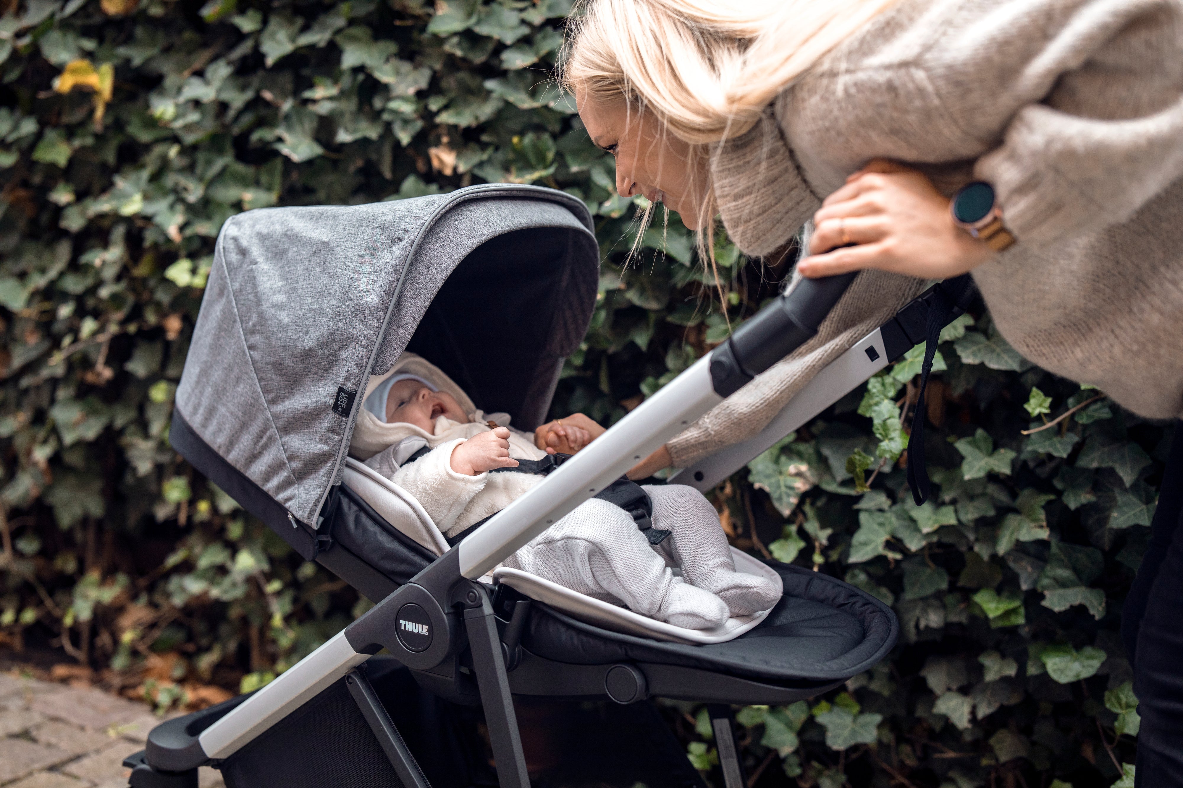 Mum playing with baby in Thule Shine Reversible & Compact City Stroller Grey Melange with Newborn Inlay
