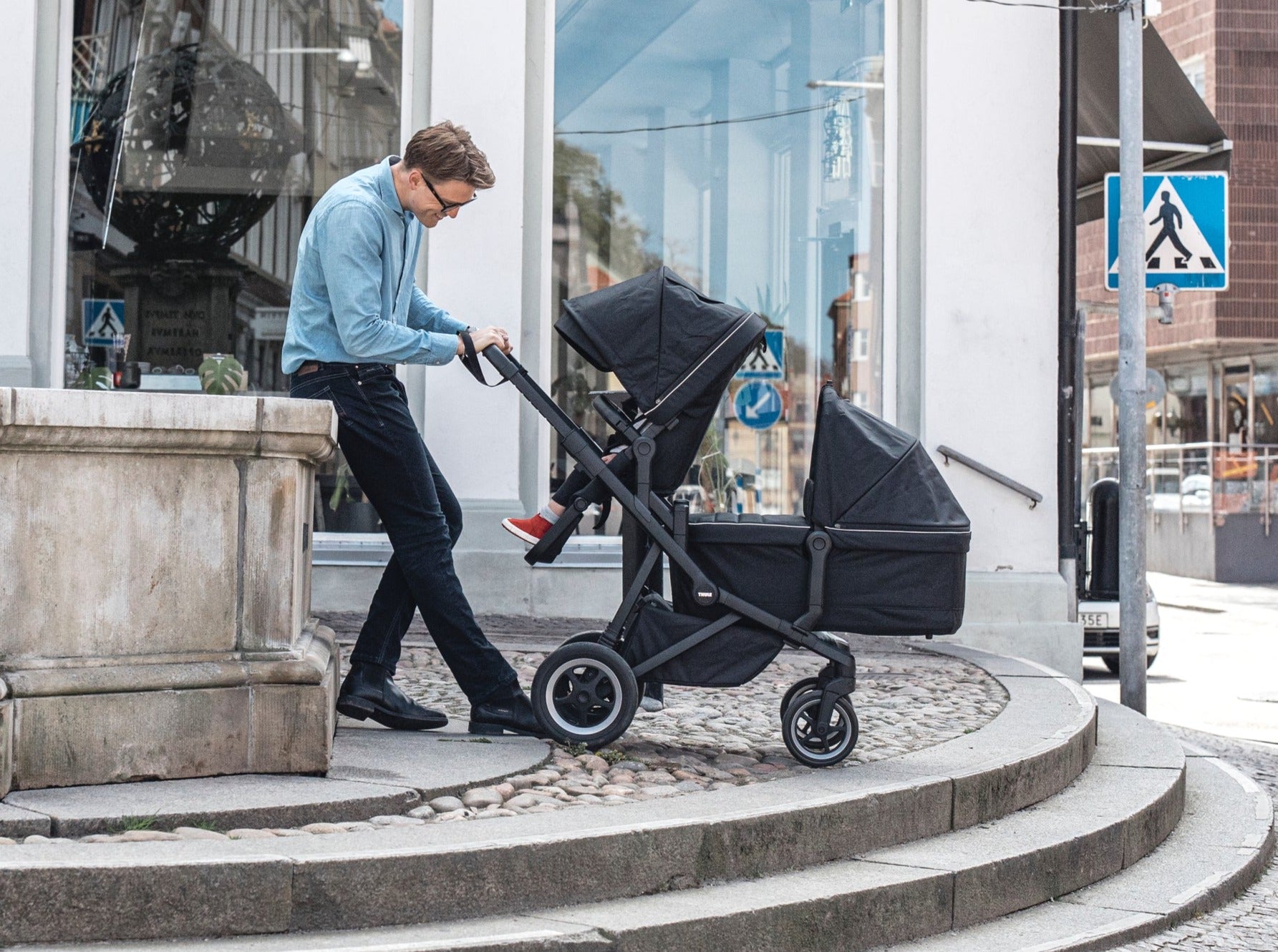 Father pushing children in Thule black sleek double stroller