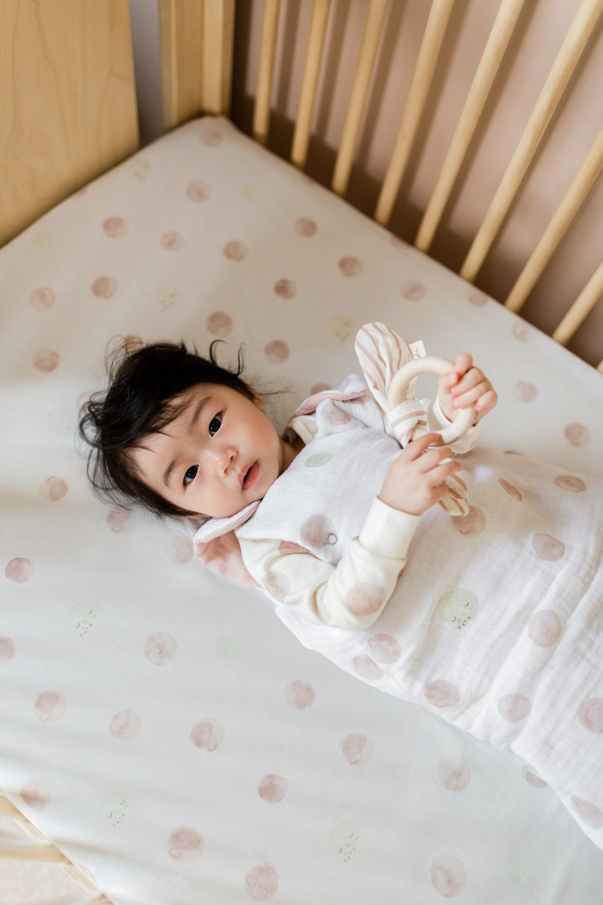 baby in crib with pehr luna dawn crib sheet