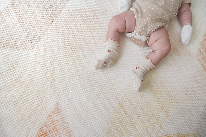 baby legs resting on lollibly sand dune playmat