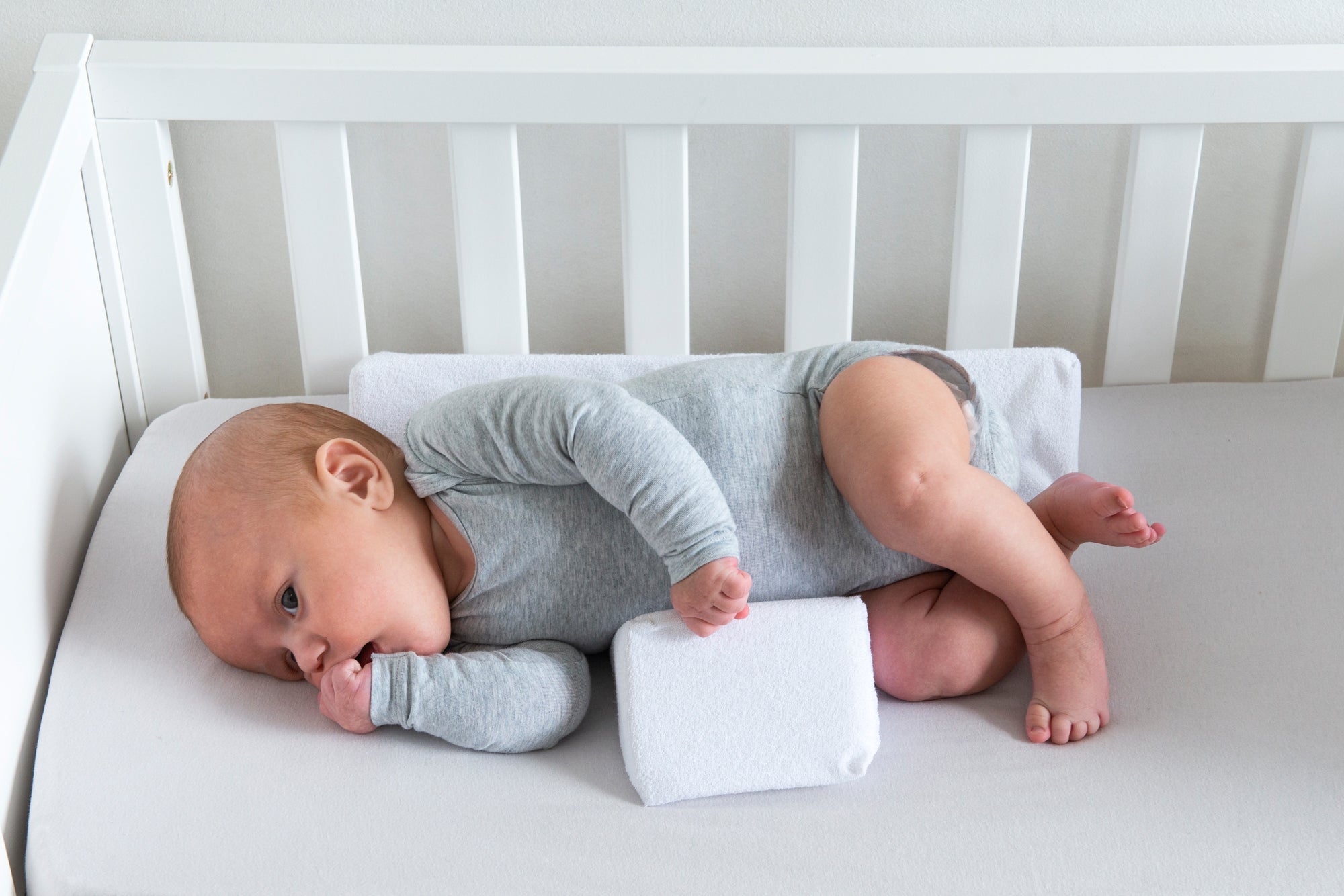 baby lying on the side with the doomoo baby sleep positioner