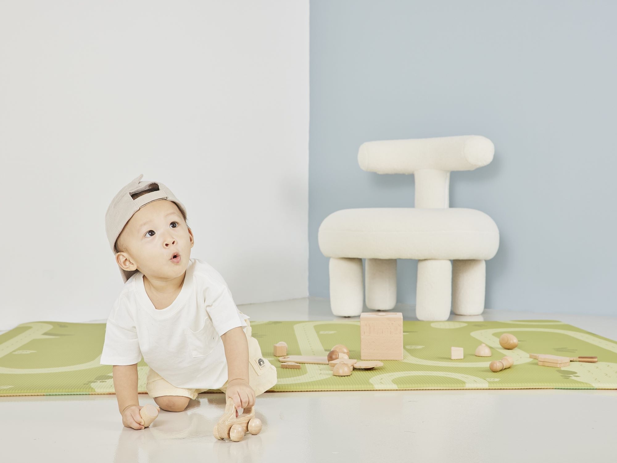 boy playing with wooden toy car on lollibly habitat playmat