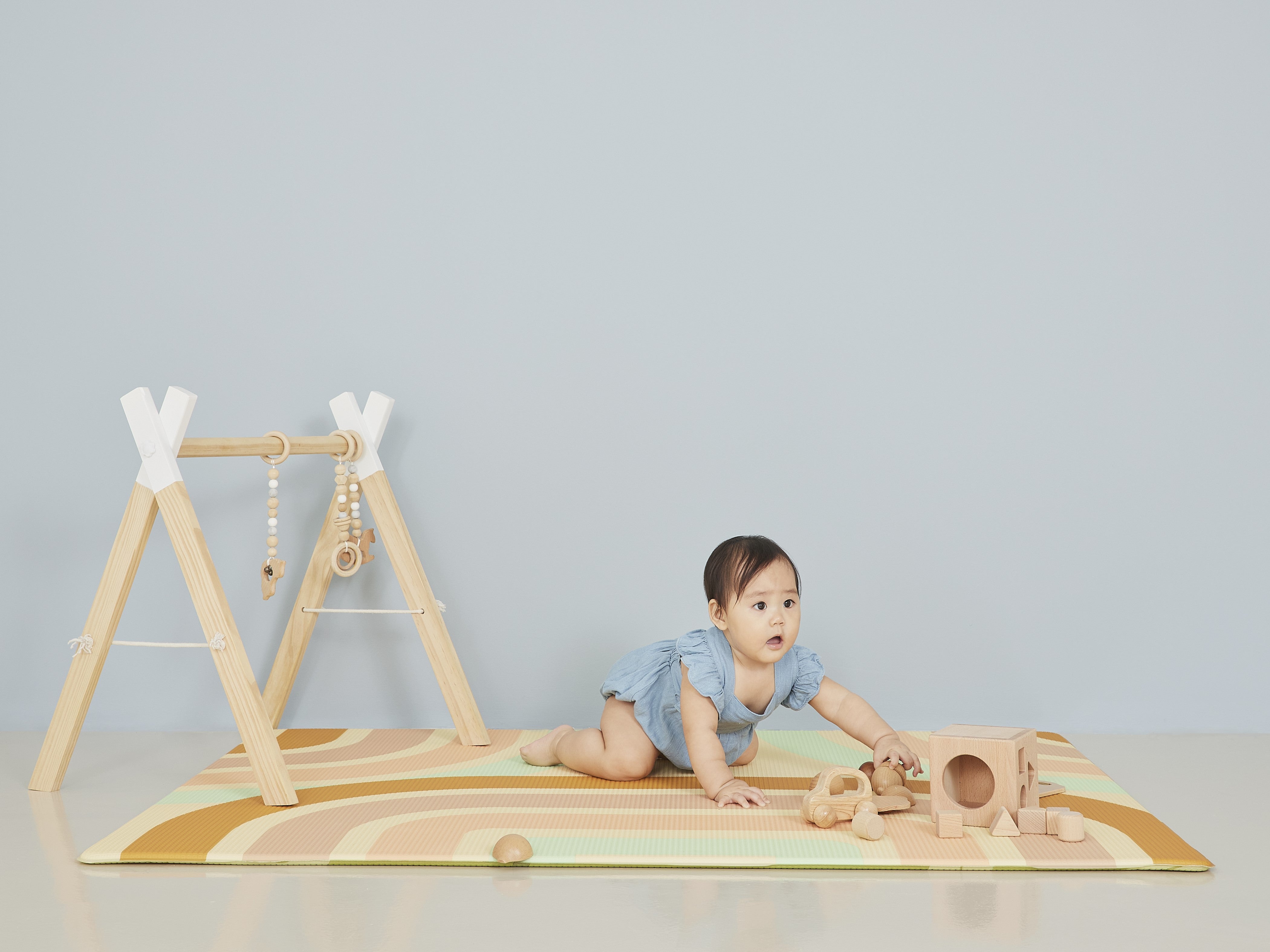 baby girl with wooden blocks on lollibly holiday play mat