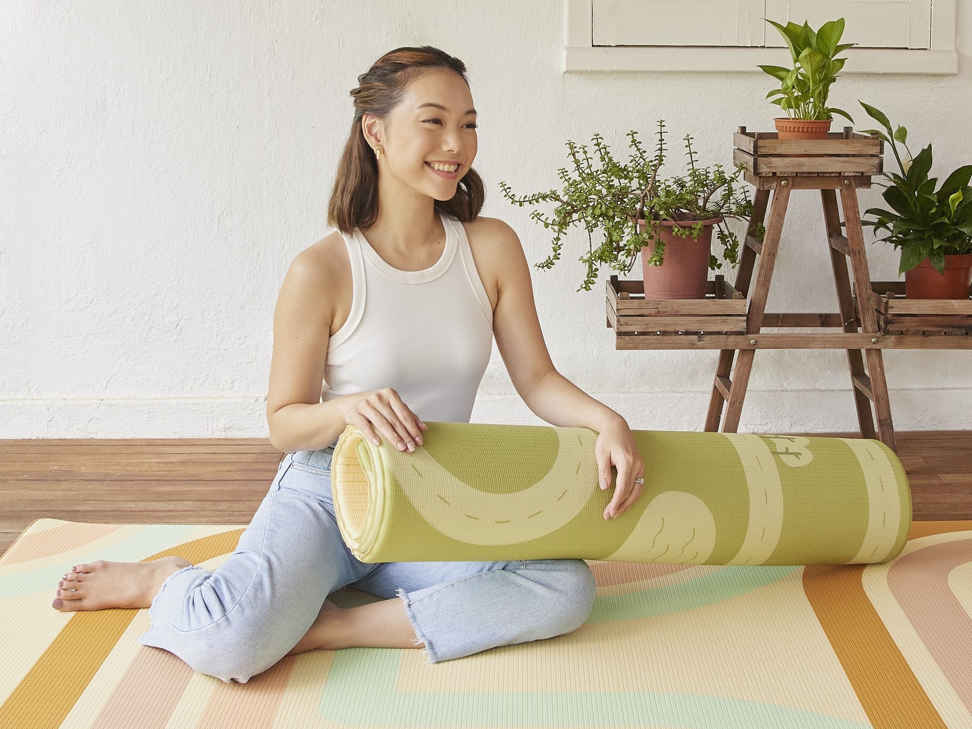 lady smiling and holding onto rolled play mat