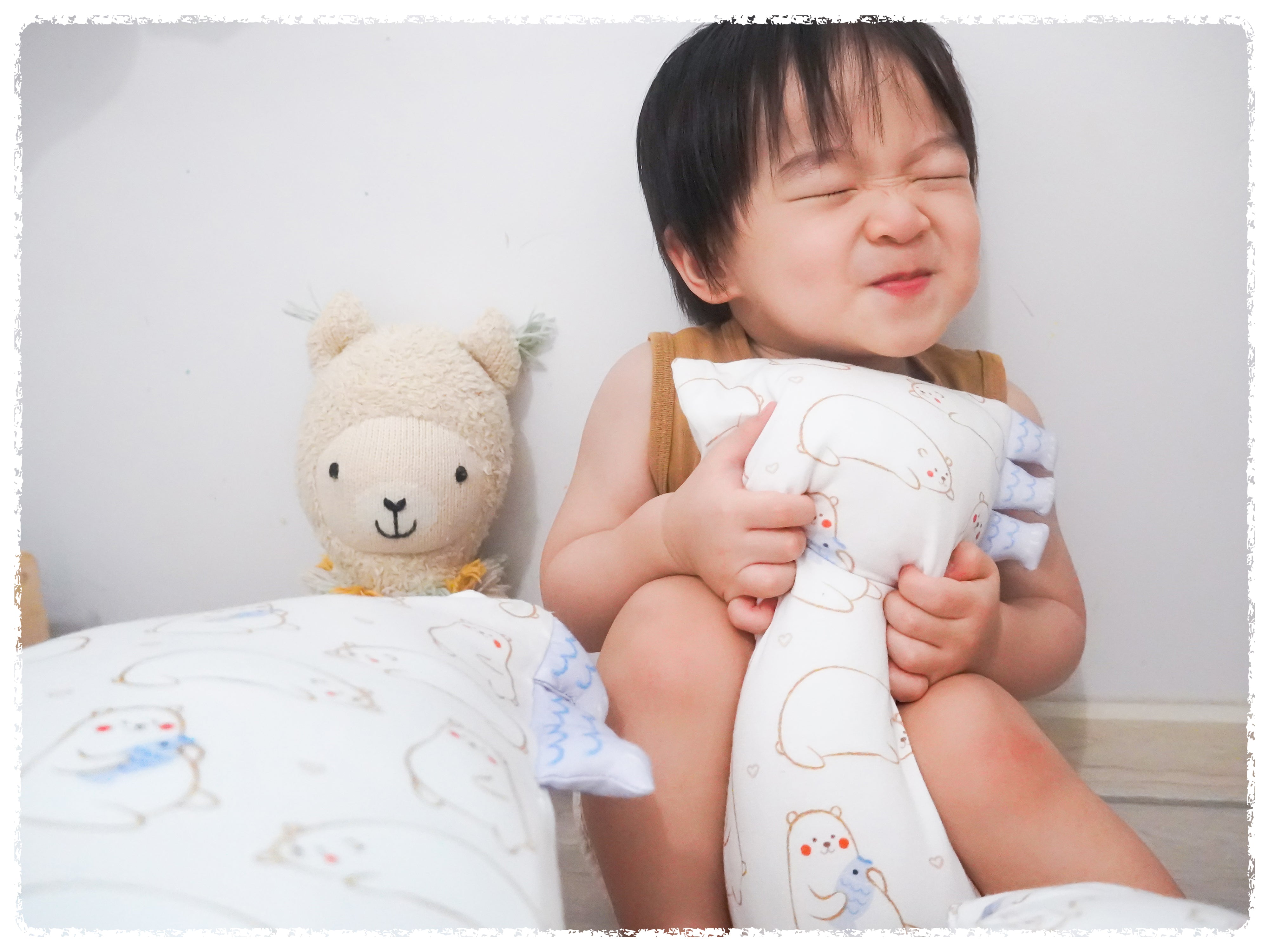 baby hugging cho maru bear pillow and smiling